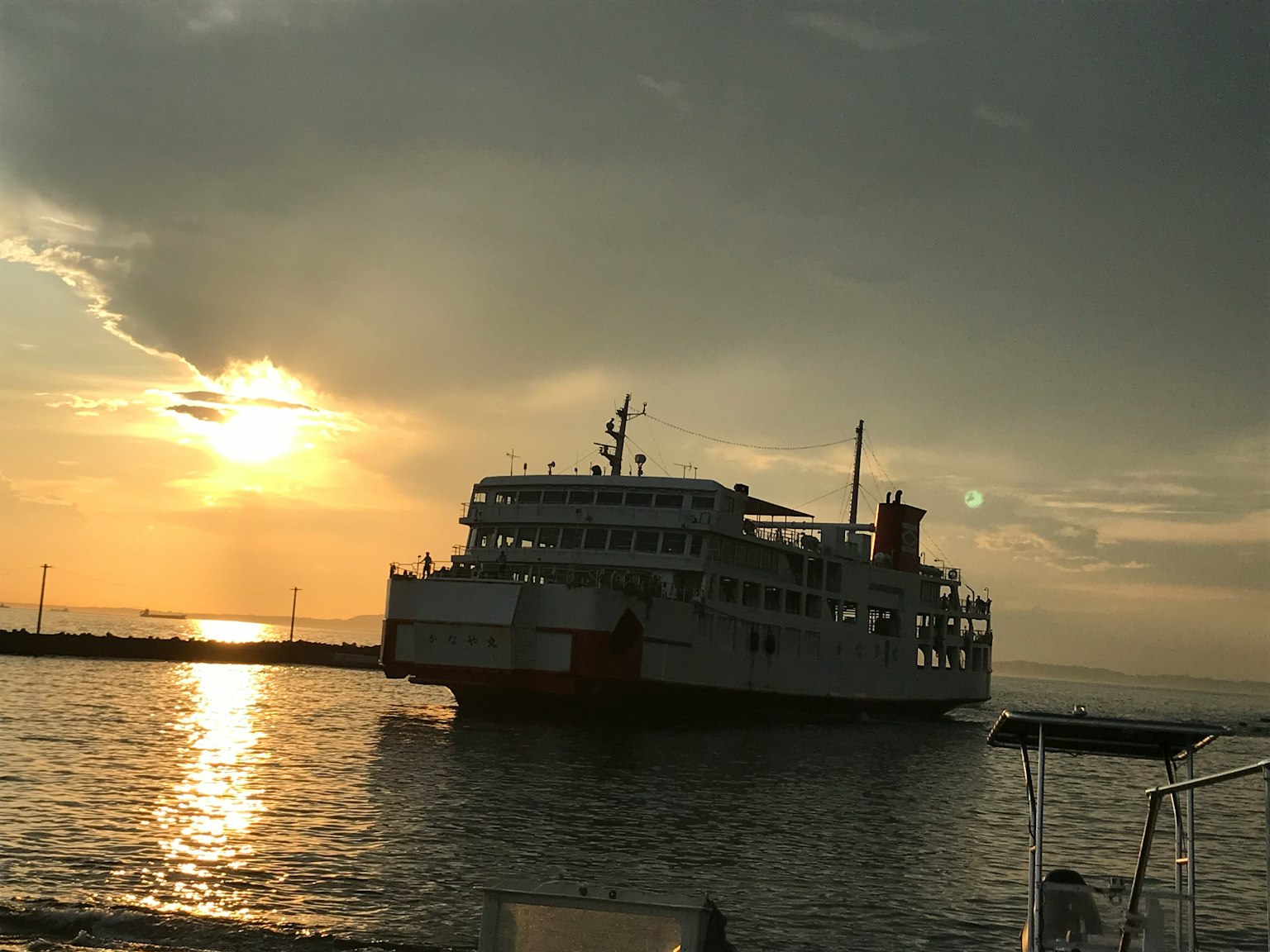 เรือข้ามฟากที่ตั้งอยู่ในฉากหลังของพระอาทิตย์ตกกับการสะท้อนบนผิวน้ำ