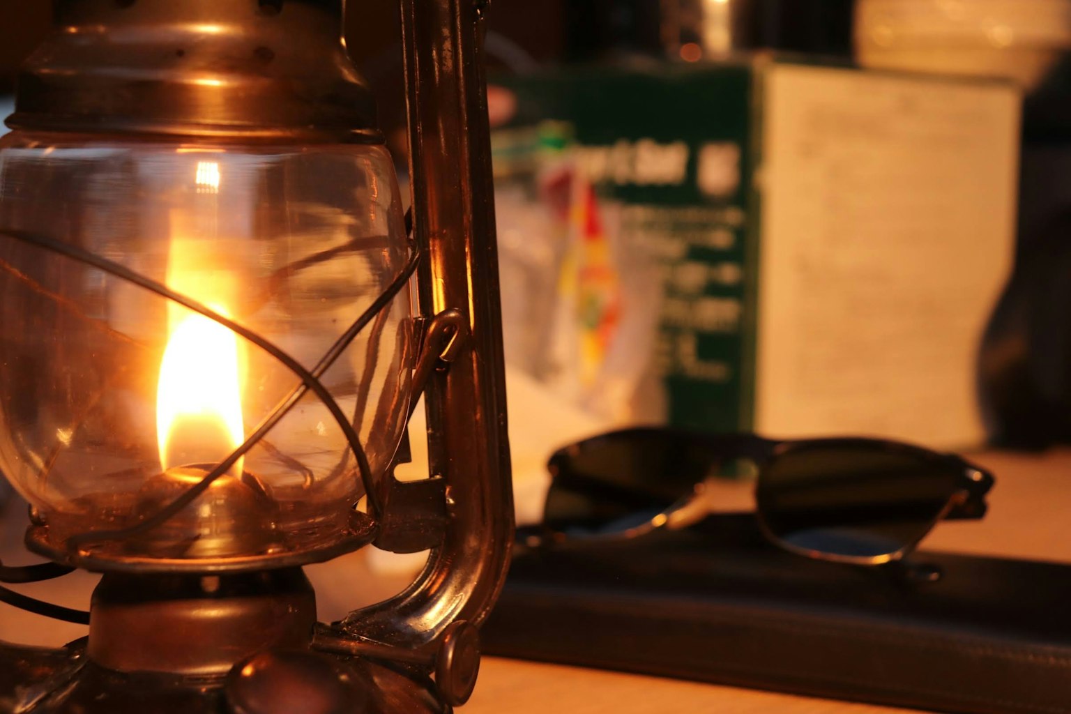 Gros plan sur la flamme d'une lanterne et des lunettes de soleil sur une table en bois