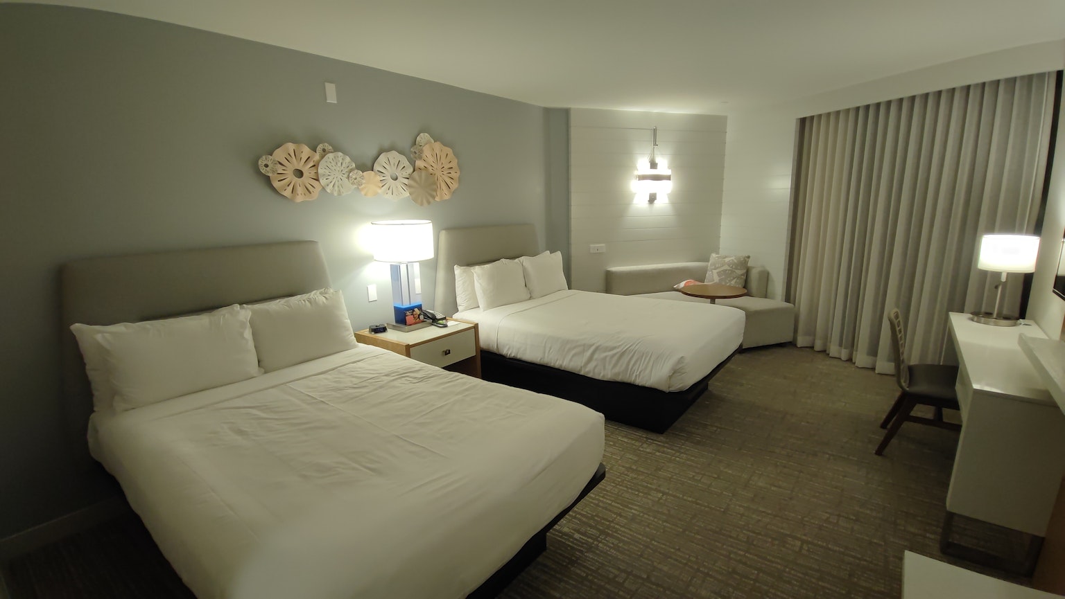 Brightly decorated hotel room featuring two double beds and a window with curtains