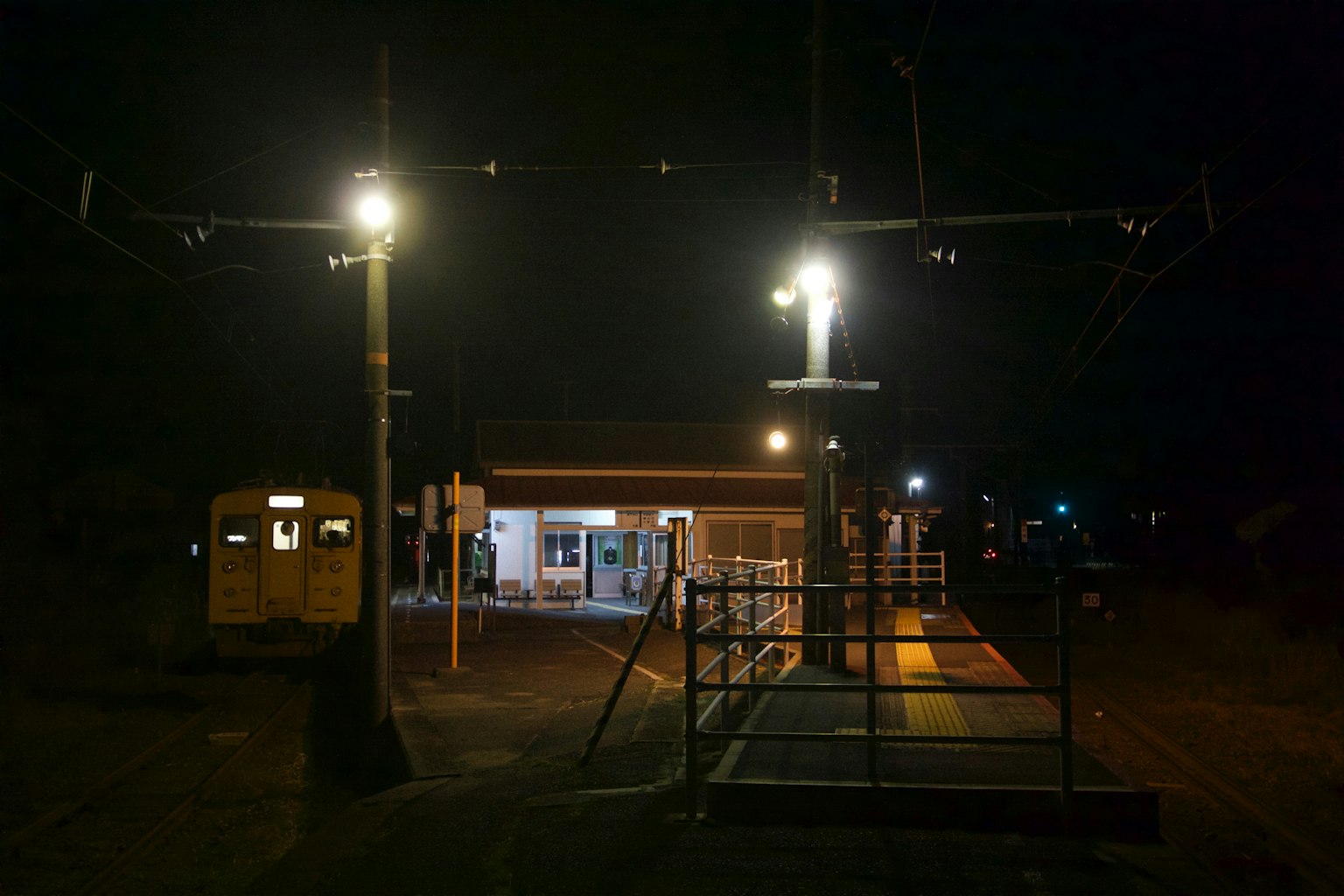Vista notturna di una stazione ferroviaria con edificio illuminato e luci