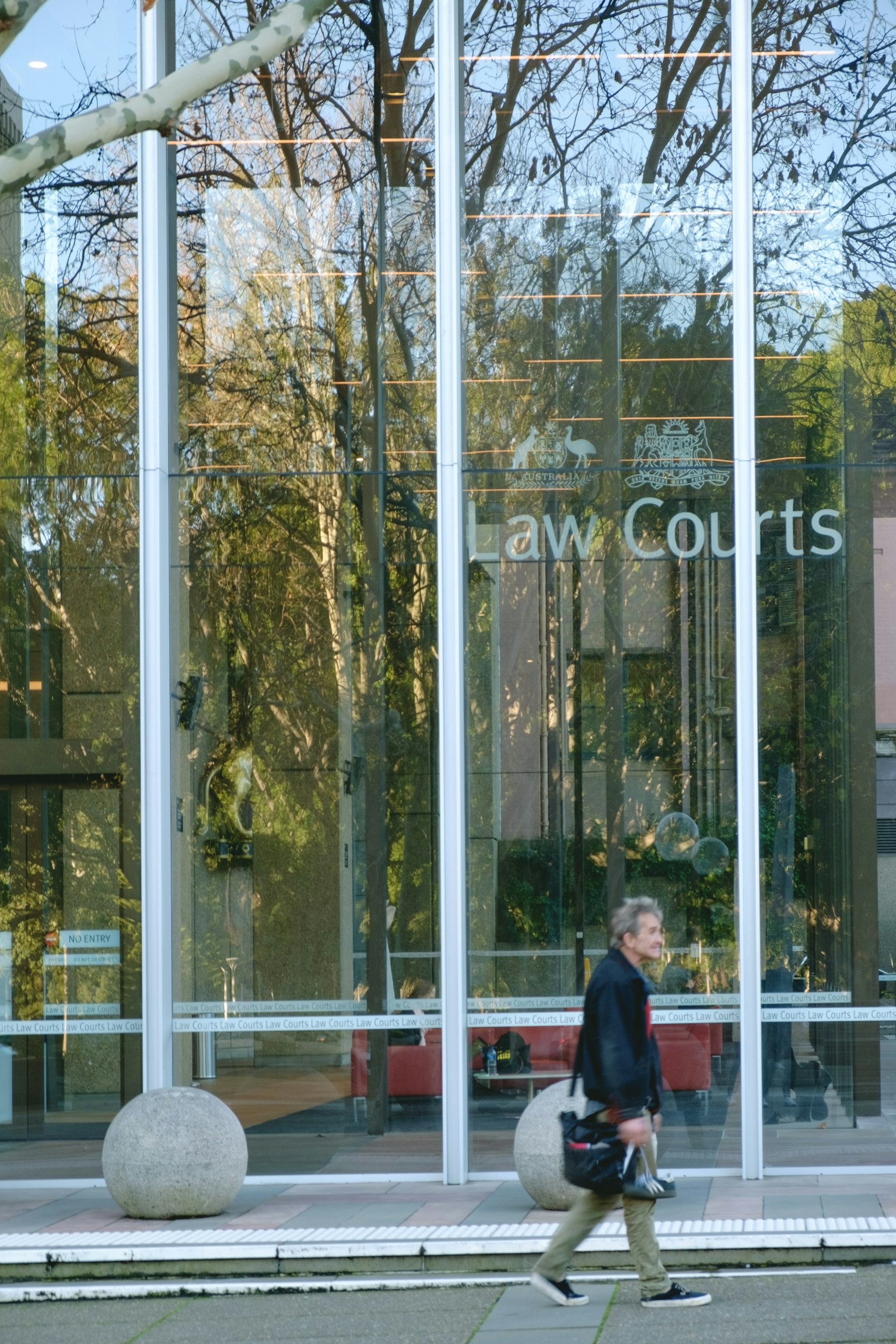 Façade en verre des tribunaux avec un passant