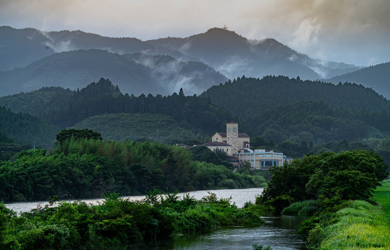 山脉和河流的风景中有一座建筑和雾气