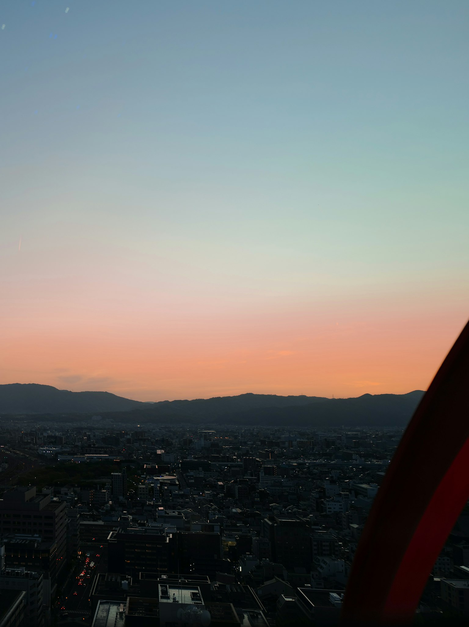 Panorama urbano al tramonto con silhouette di montagne