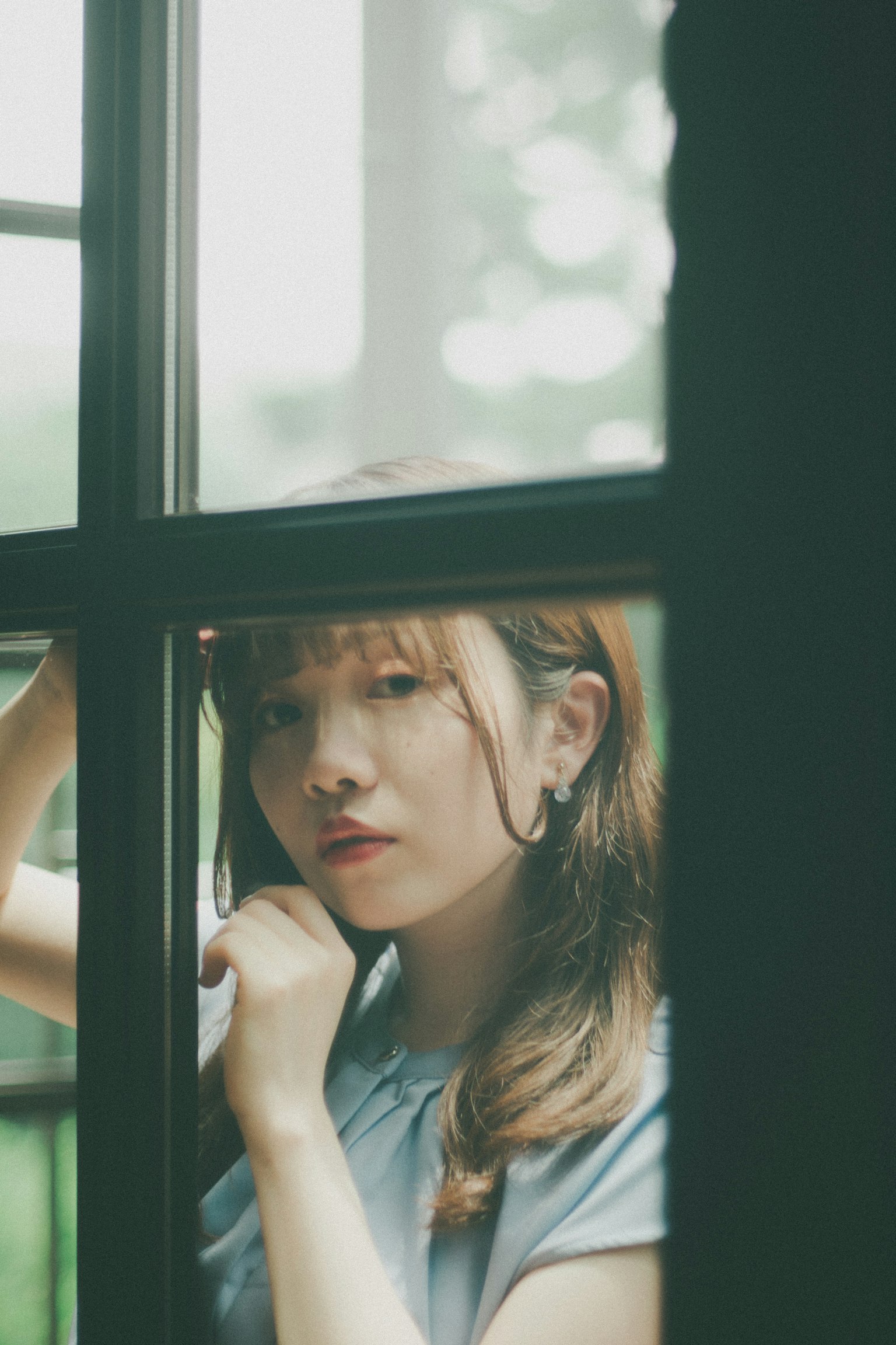 Portrait of a woman looking through a window soft light filtering in
