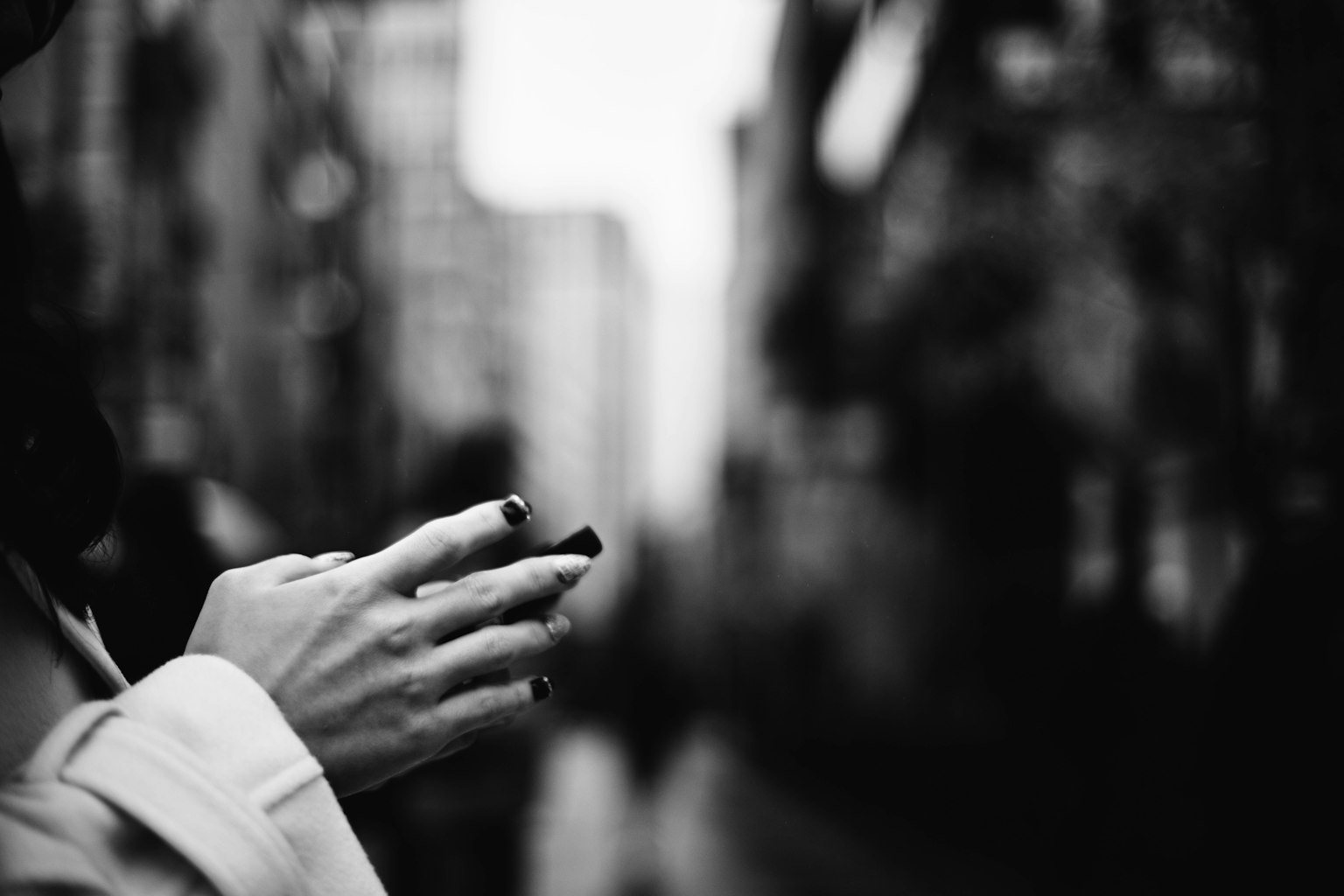 Black and white street photo featuring hands holding a smartphone