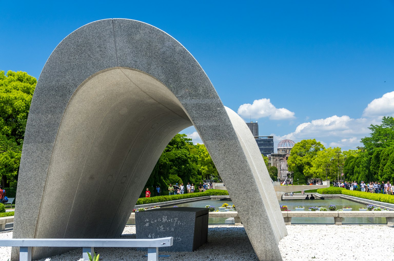 Escultura moderna de arco de concreto en un parque con vegetación circundante