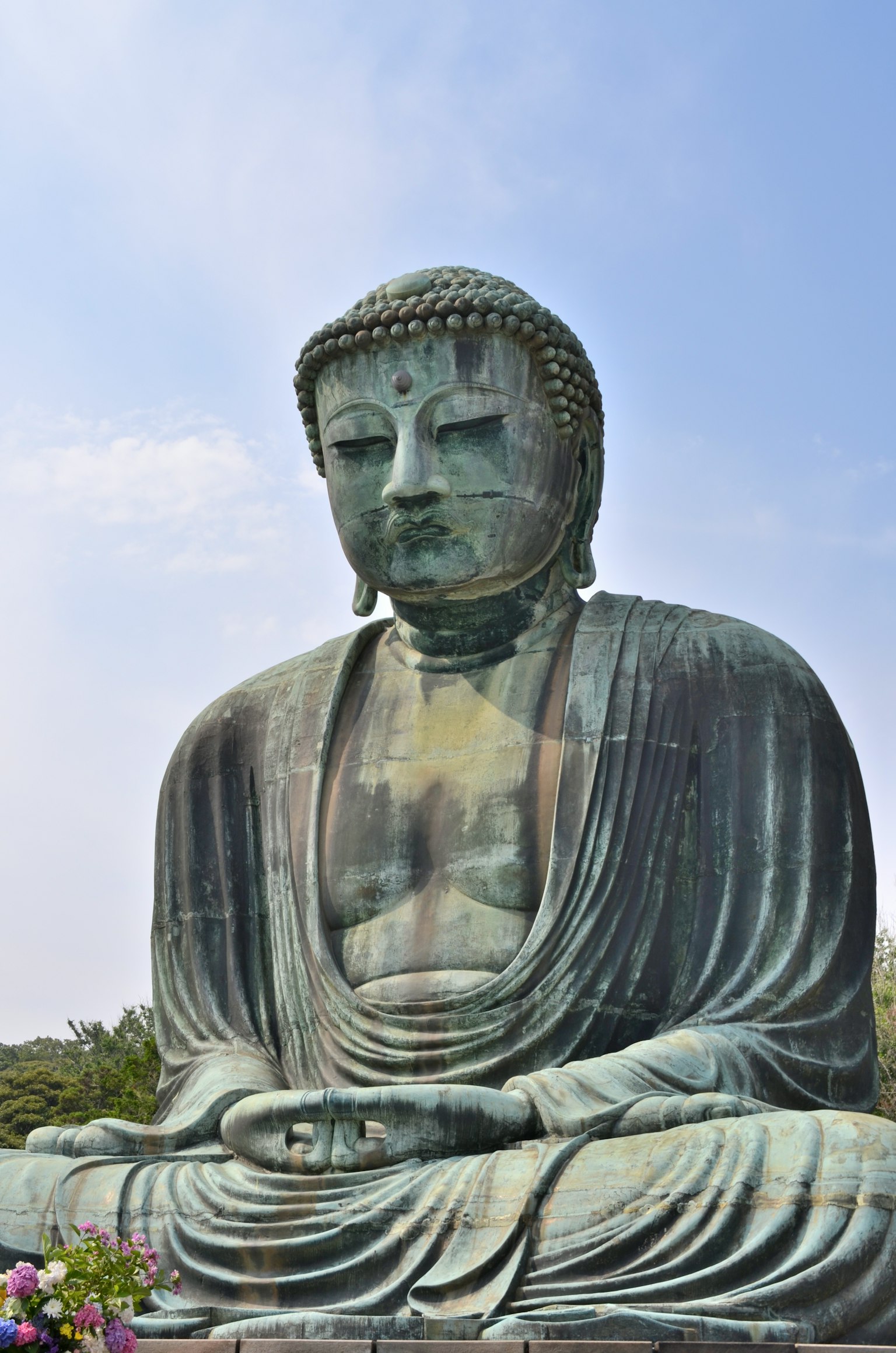 A seated Buddha statue under a blue sky