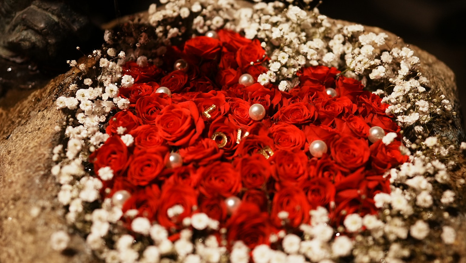 Herzförmige Anordnung aus roten Rosen und Perlen