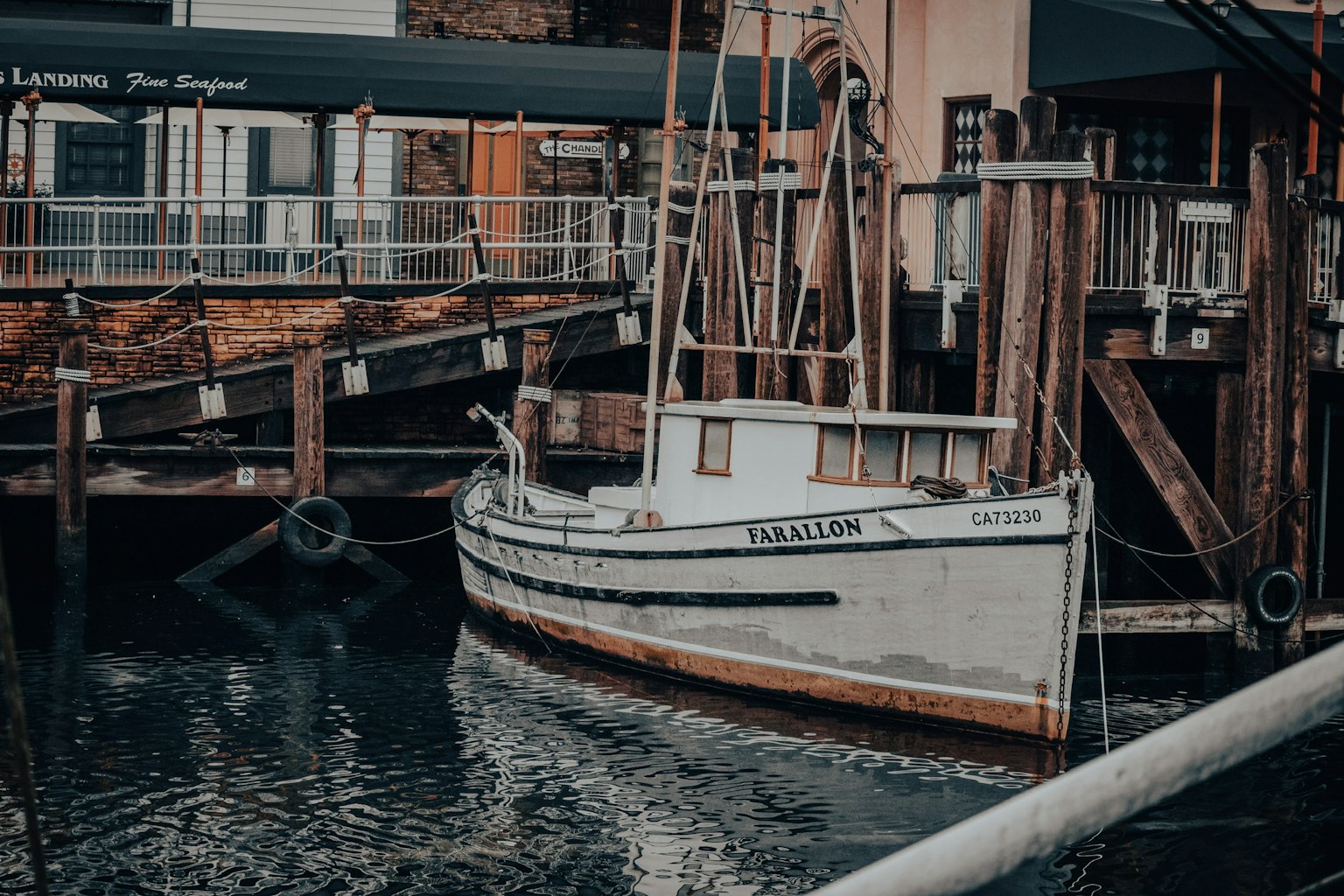 White fishing boat docked at a harbor with wooden piers