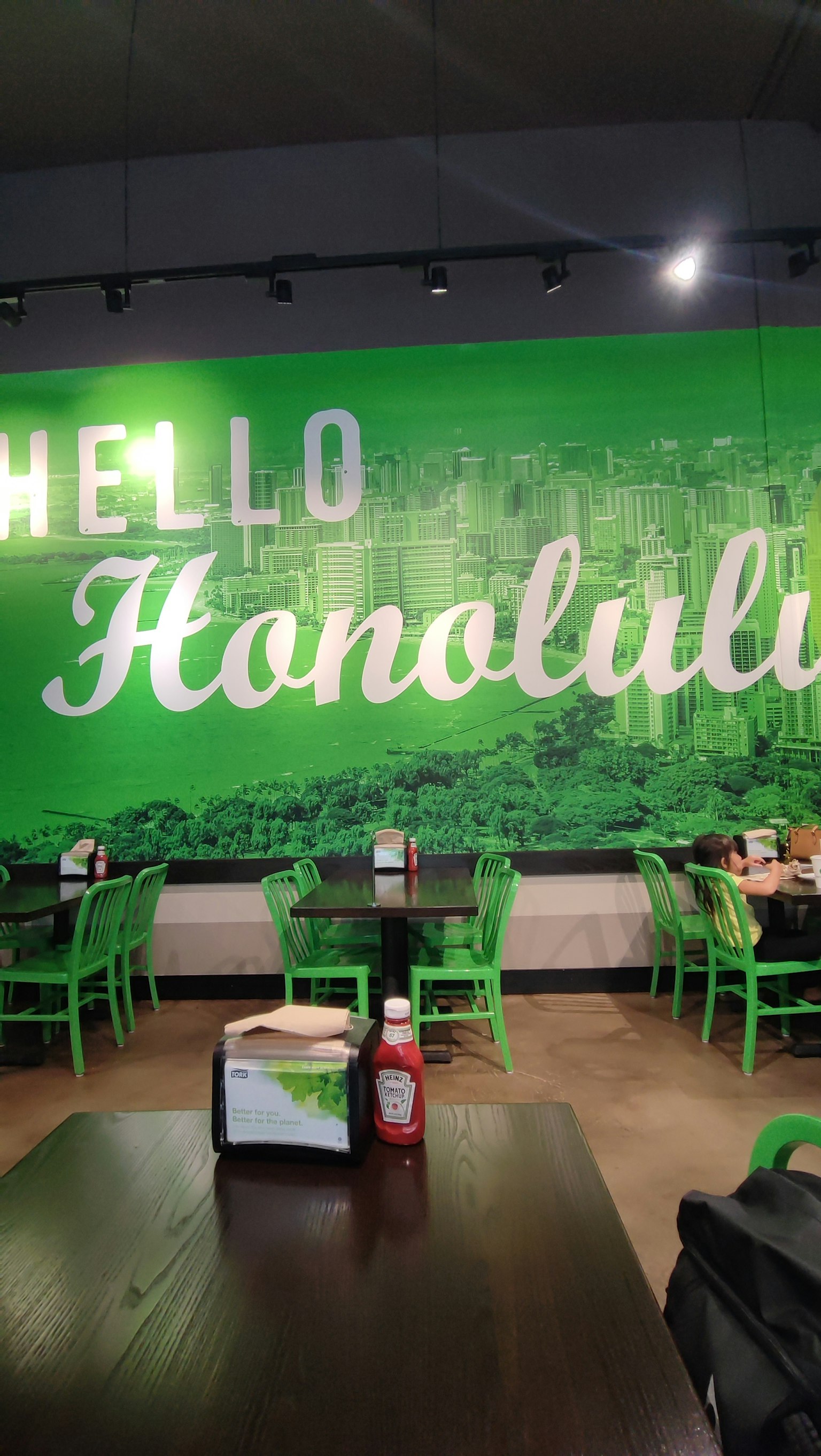 Innenansicht eines Cafés mit grüner Wand und dem Text Hallo Honolulu