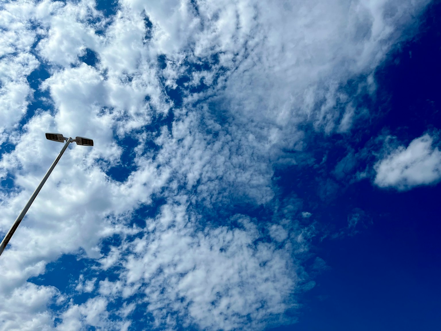 Klarer blauer Himmel mit weißen Wolken und einer Straßenlaterne