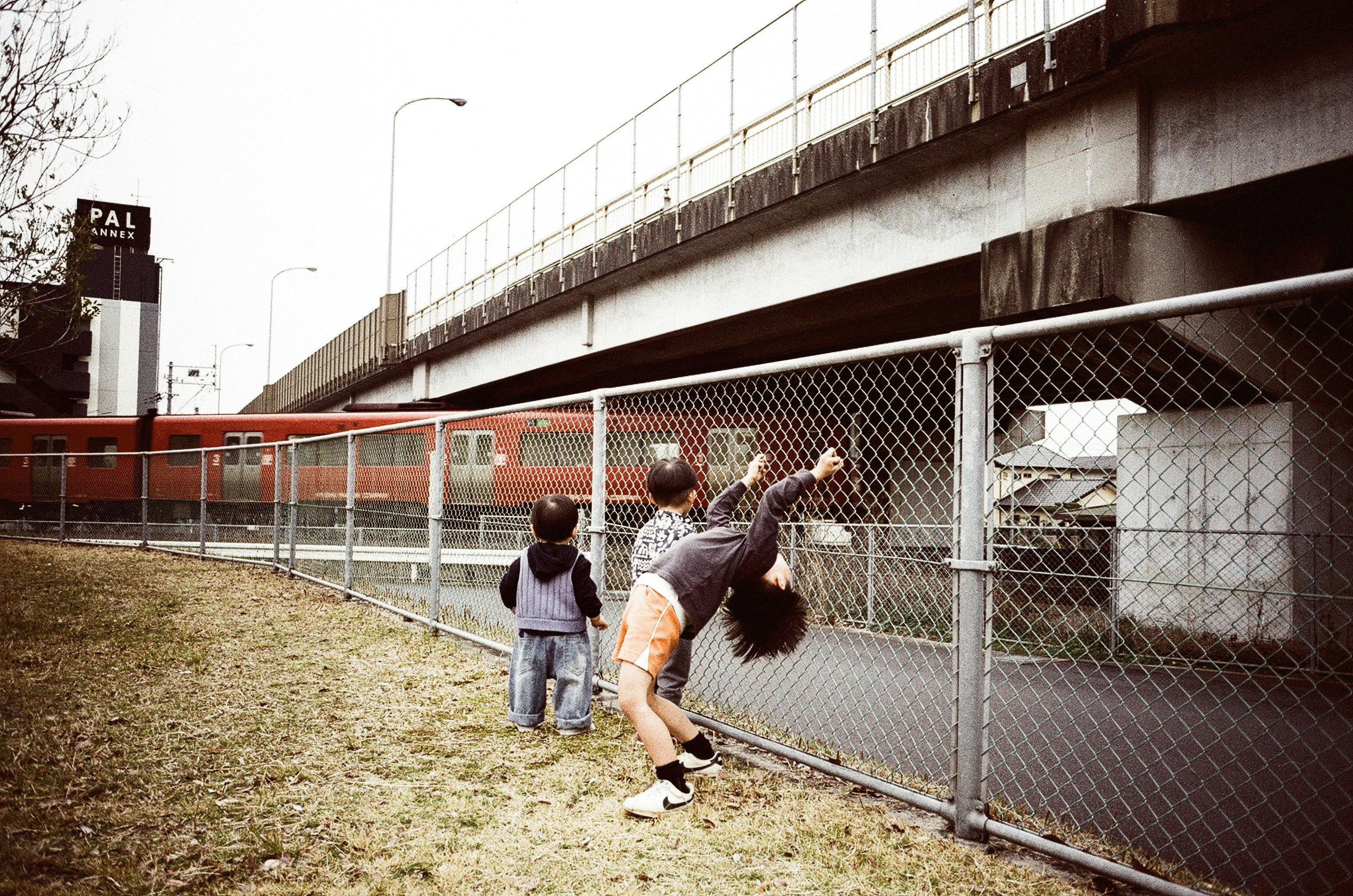 parent and child looking up at a train from beside a fence
