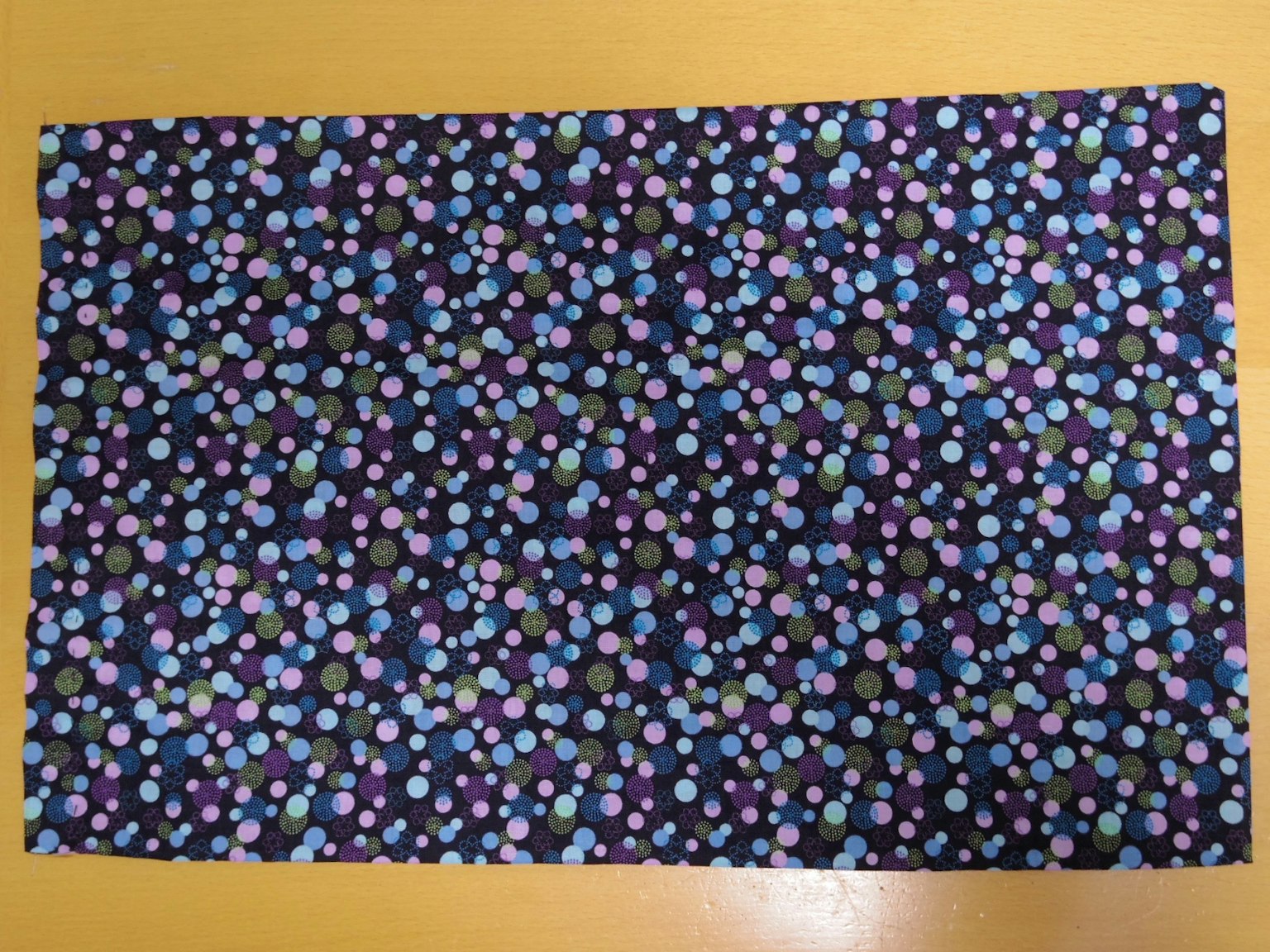Fabric with a purple background and scattered blue and pink dots