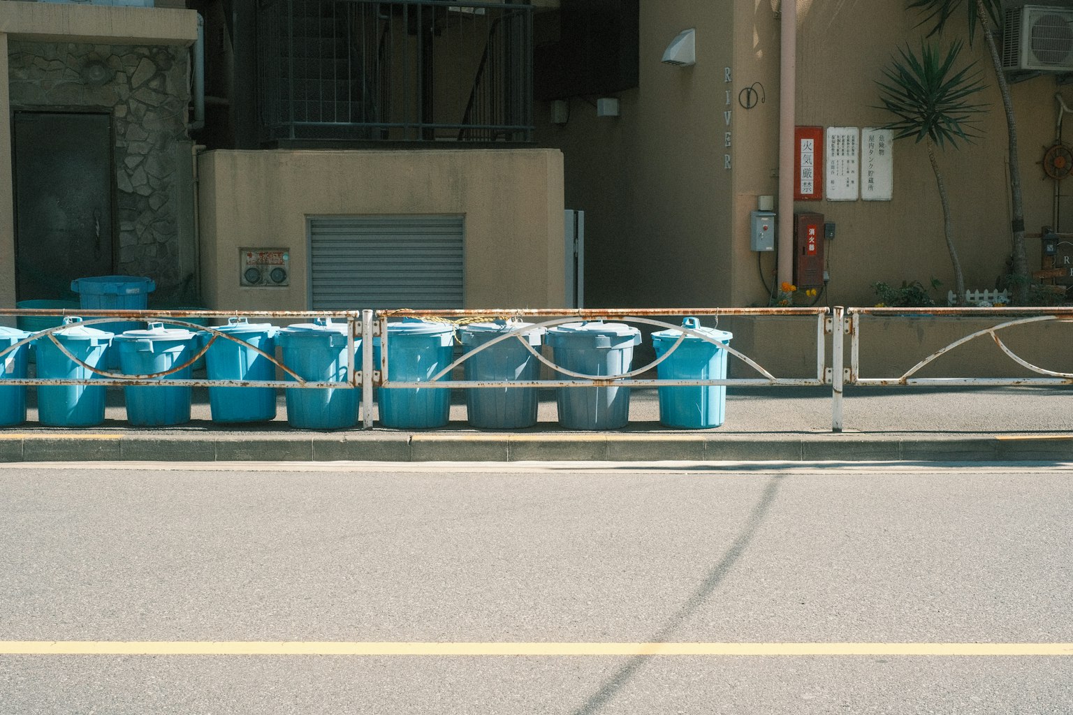 Row of blue trash bins along a street