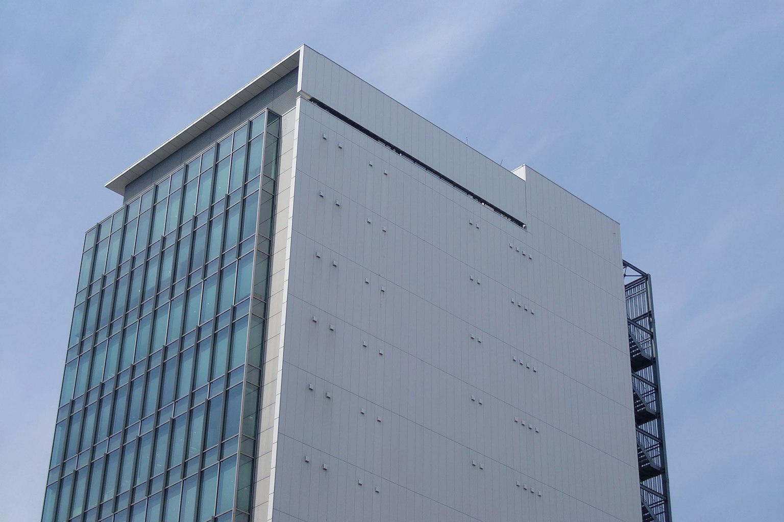 세련된 디자인의 고층 빌딩이 파란 하늘을 배경으로 유리 파사드를 특징으로 함