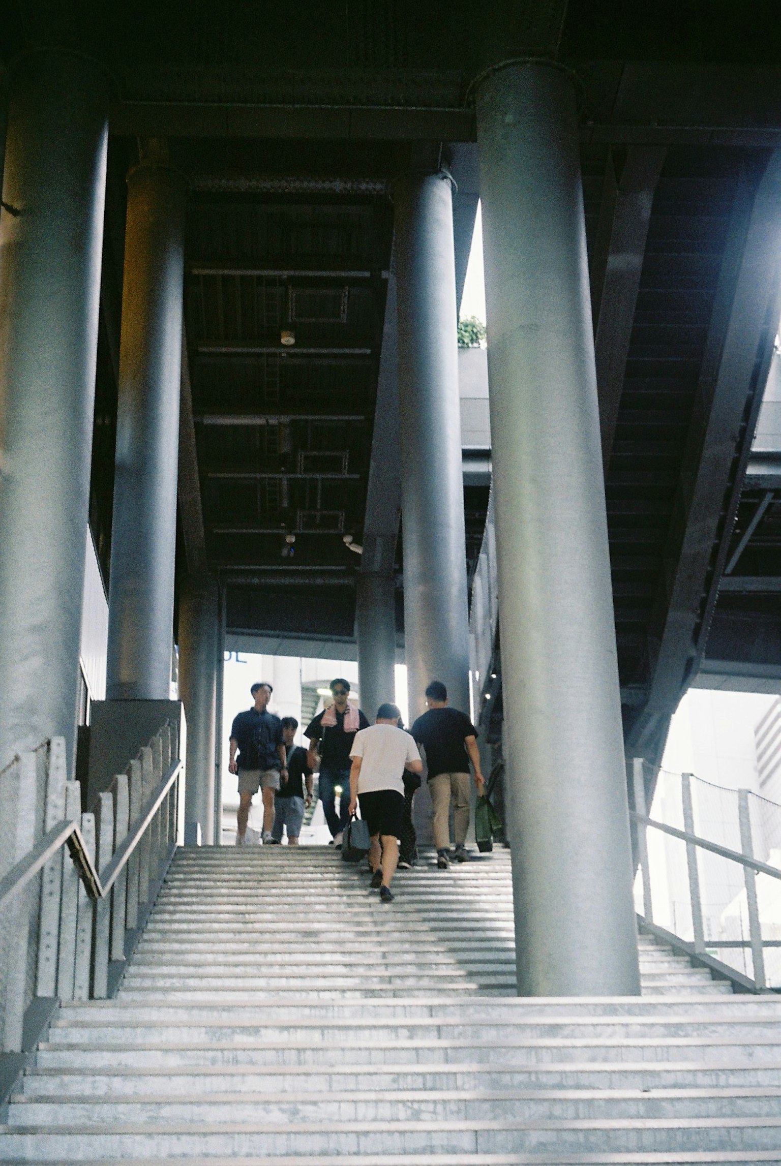A group of people ascending a modern staircase with metallic pillars