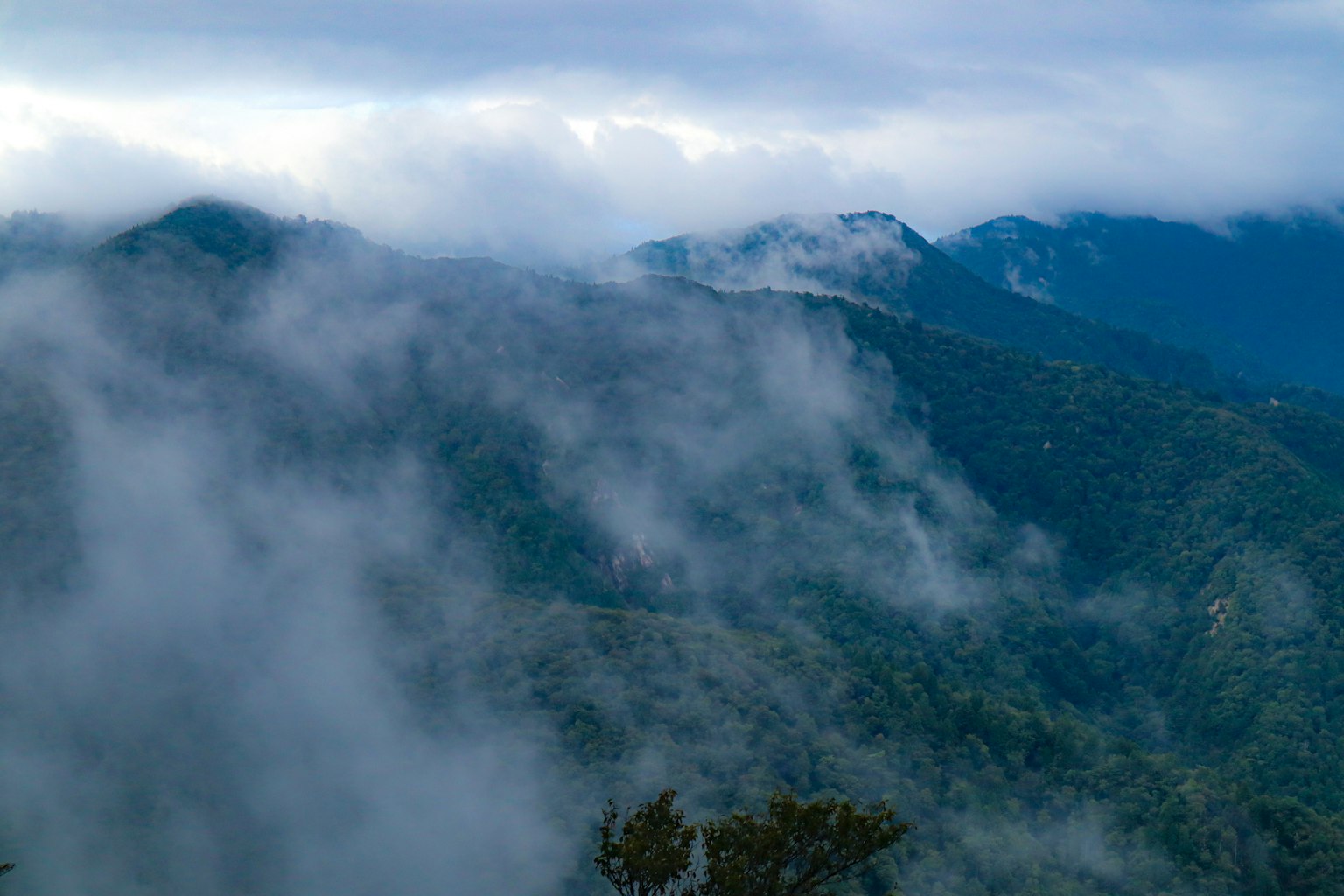 Un paisaje montañoso brumoso con colinas onduladas y cielos nublados