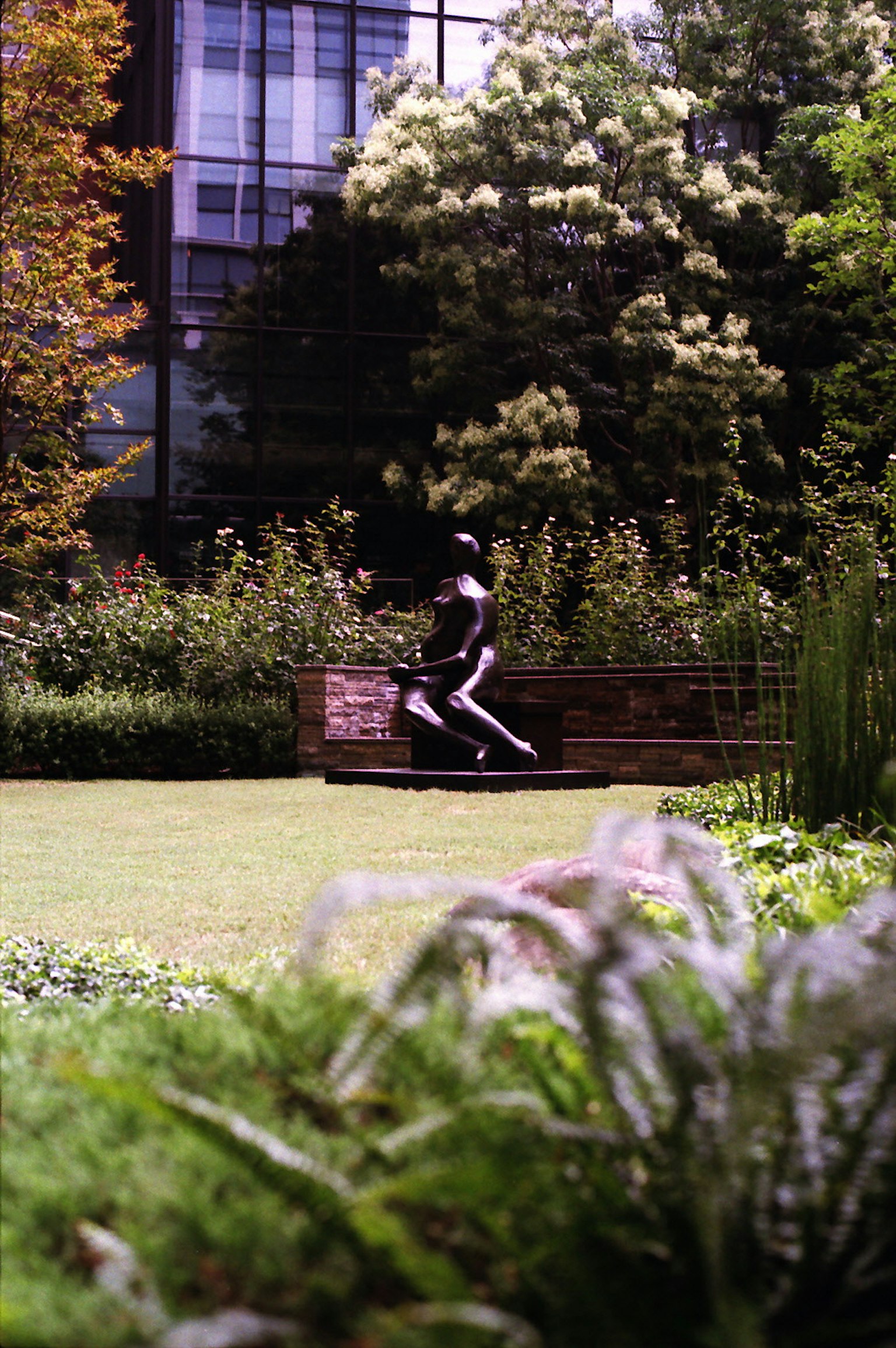 Une sculpture noire dans un parc vert avec des arbres et des bâtiments