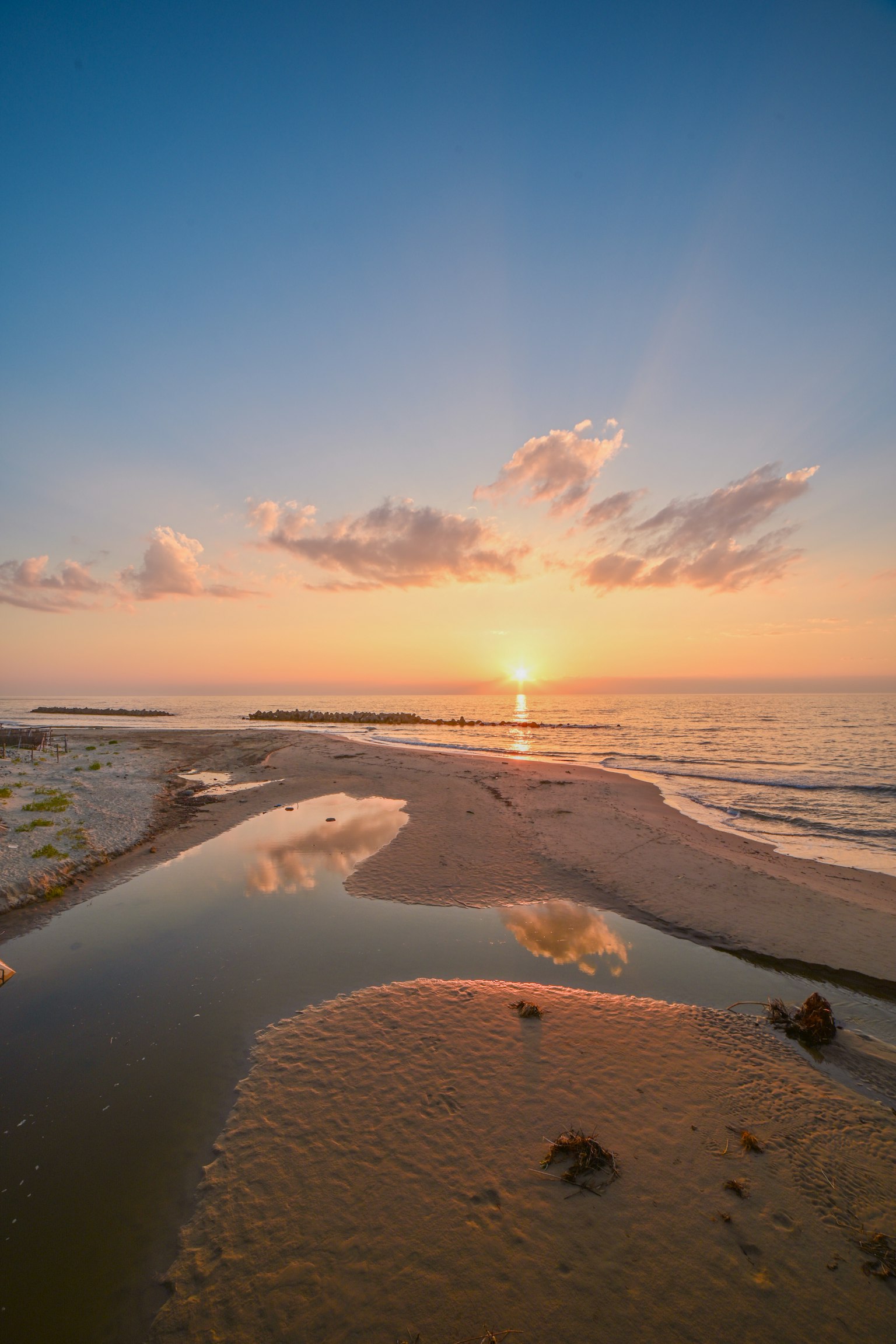 Beautiful coastal landscape with a sunset over the sea tidal flats and puddles reflecting the light