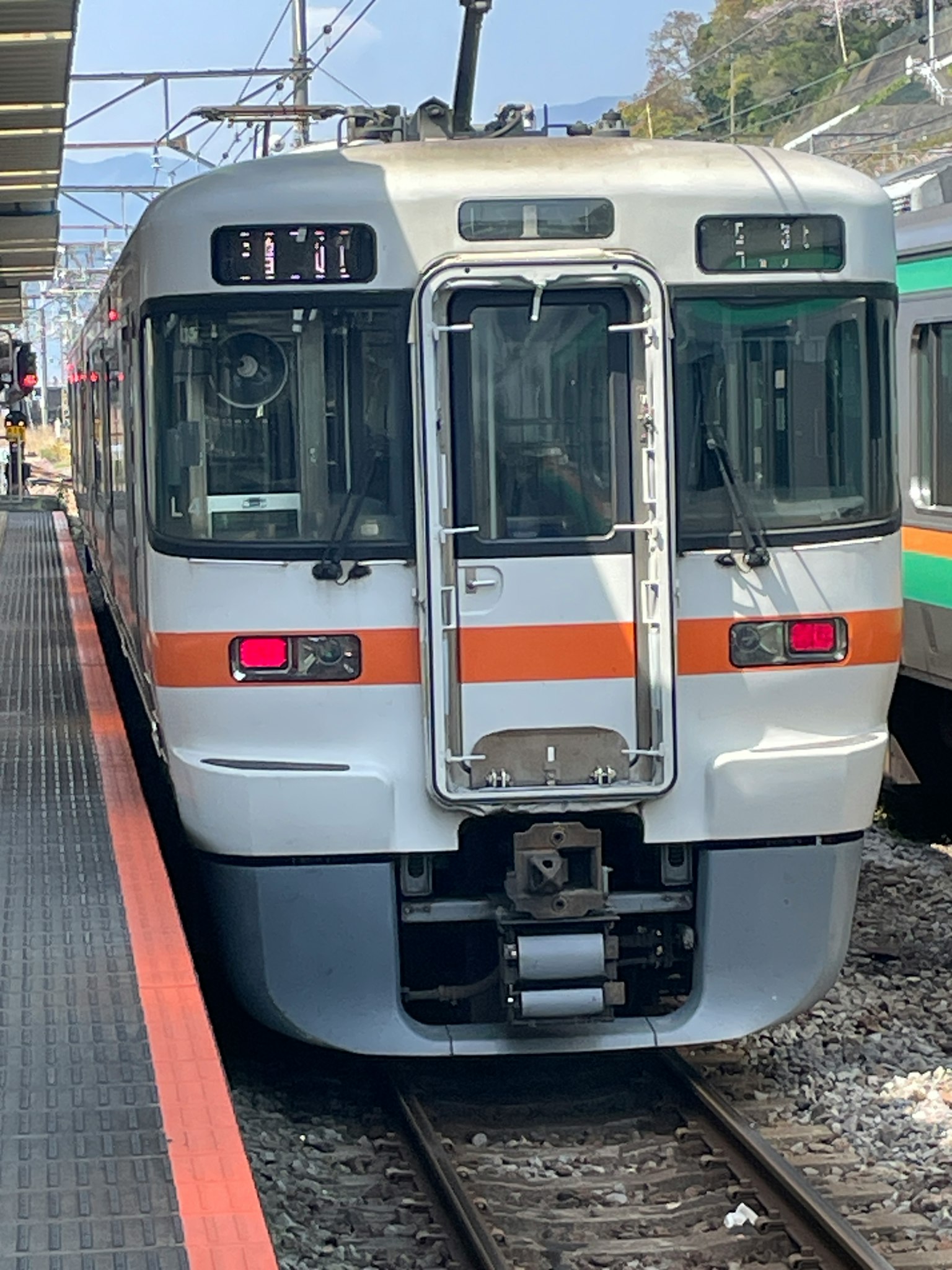 Ein Zug in Orange und Weiß steht an einem Bahnhof