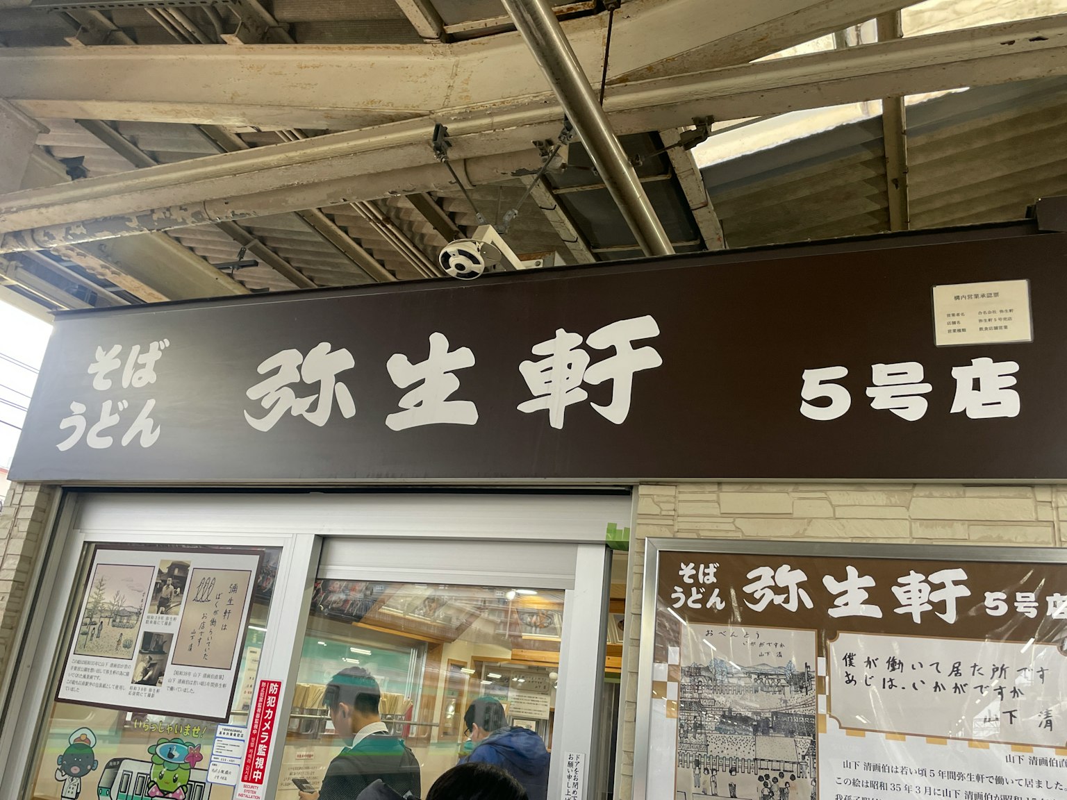 Schild eines Soba-Restaurants am Bahnhof mit schwarzem Hintergrund und weißen Buchstaben