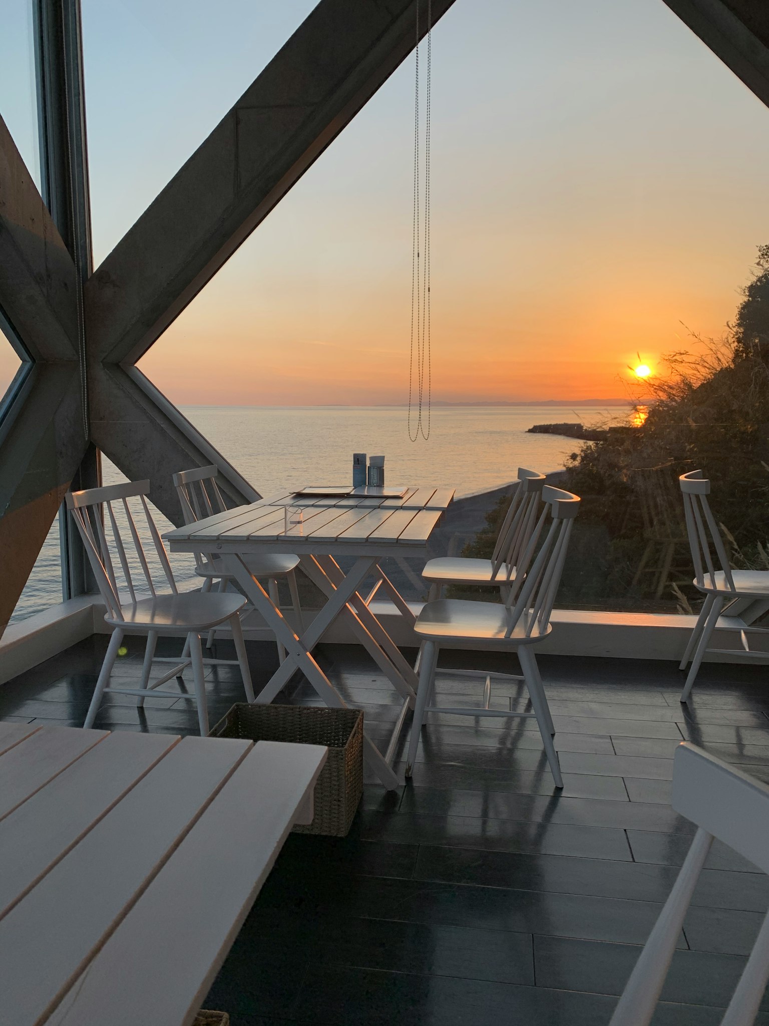 Area pranzo moderna con vista sul tramonto sul mare Tavolo e sedie bianche disposte