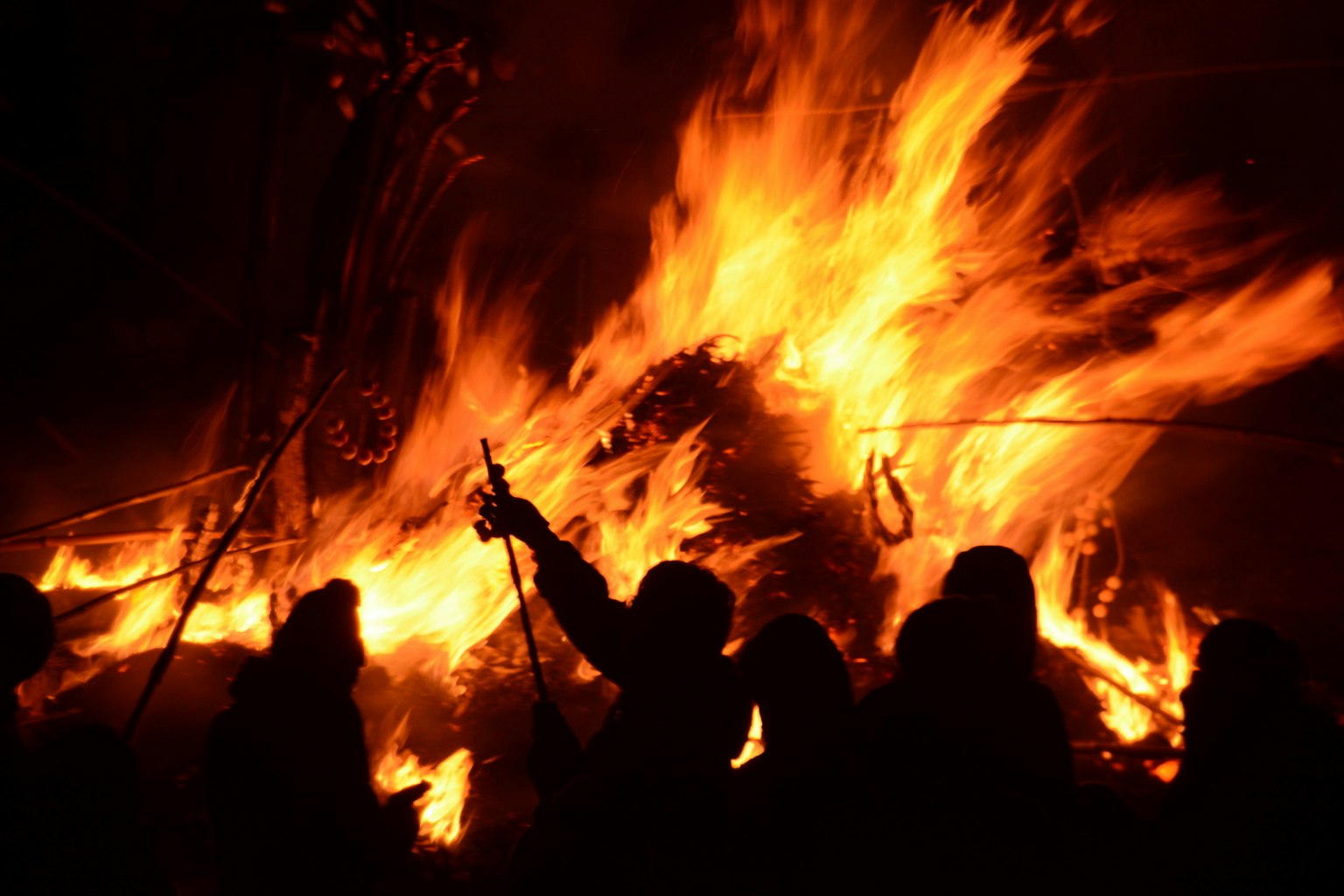 Menschen versammelt um ein großes Feuer in der Nacht