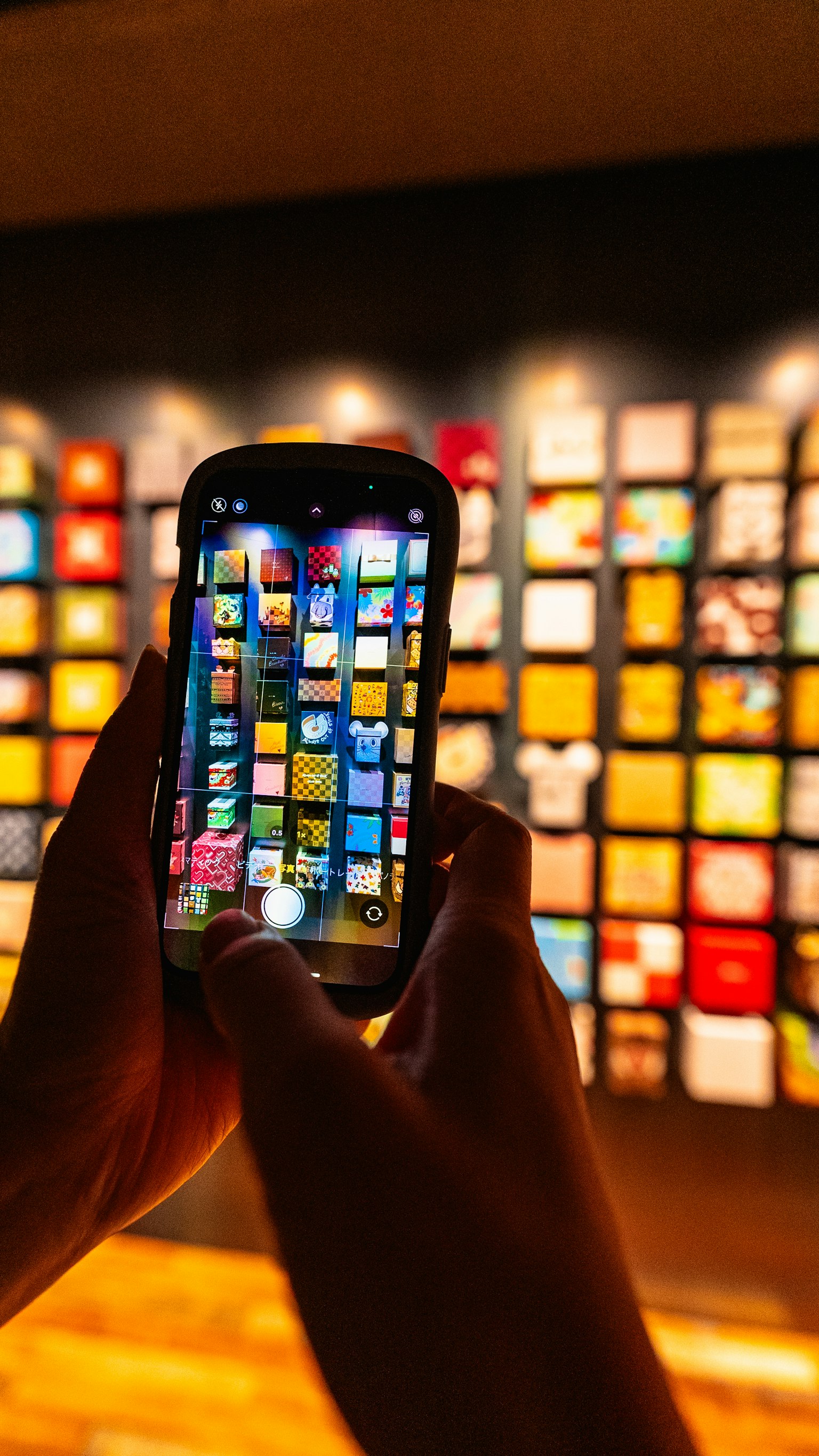 Uno smartphone tenuto in mano che mostra immagini colorate di fronte a un muro vivace