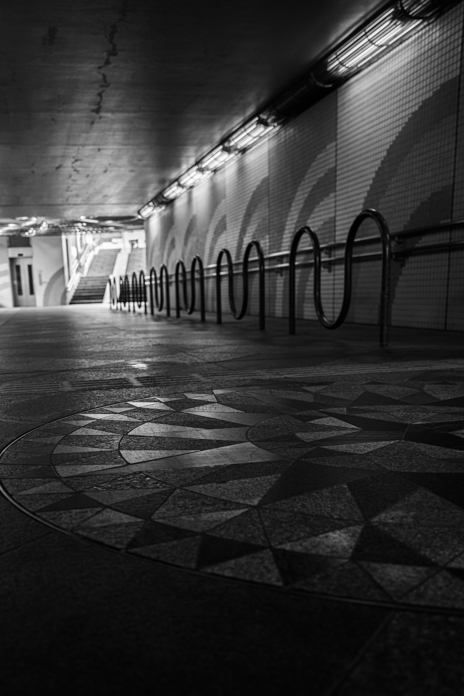 A view of a subway tunnel featuring intricate mosaic patterns and bicycle racks