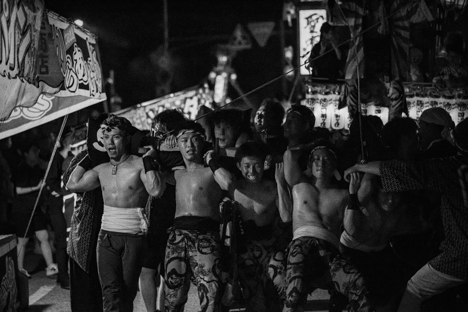 黑白照片，男人們在節日中抬著一個便攜神社