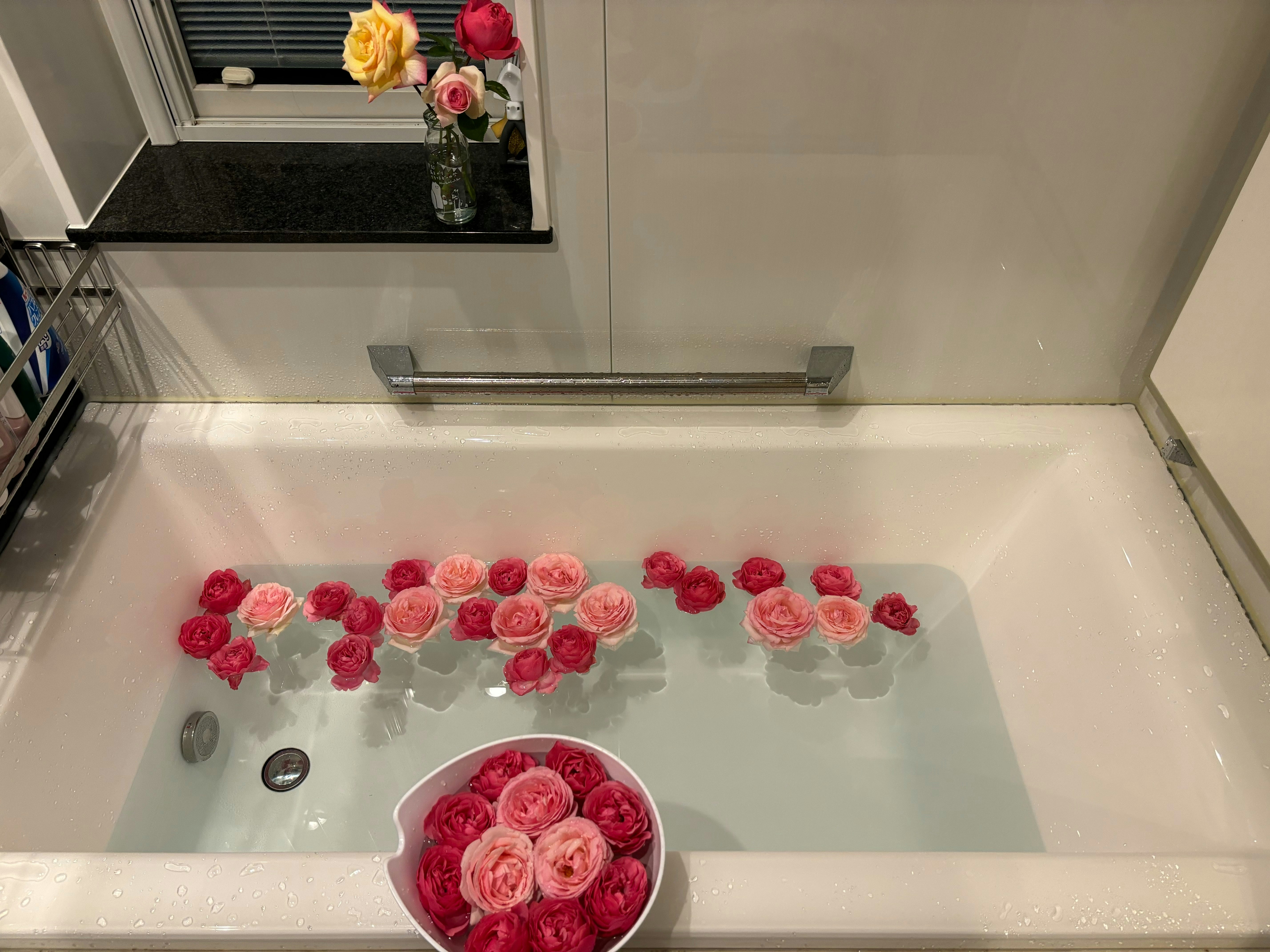 vasca da bagno con petali di rose galleggianti e decorazione floreale