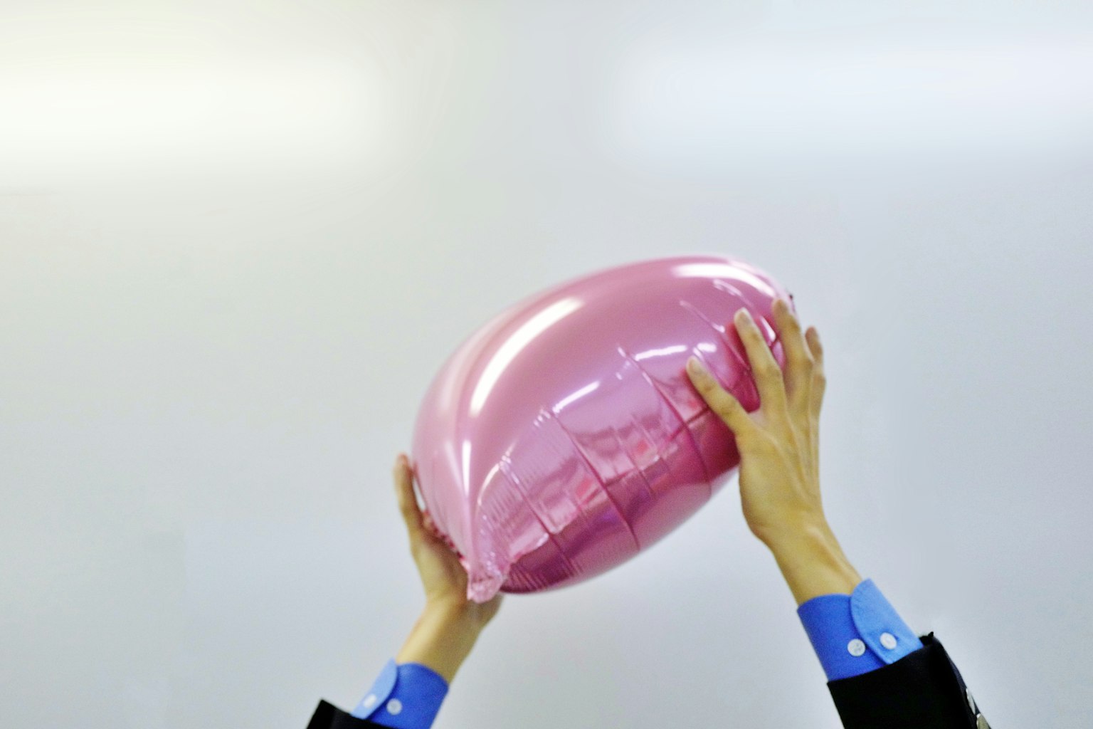 Une personne tenant un grand objet en forme de ballon rose
