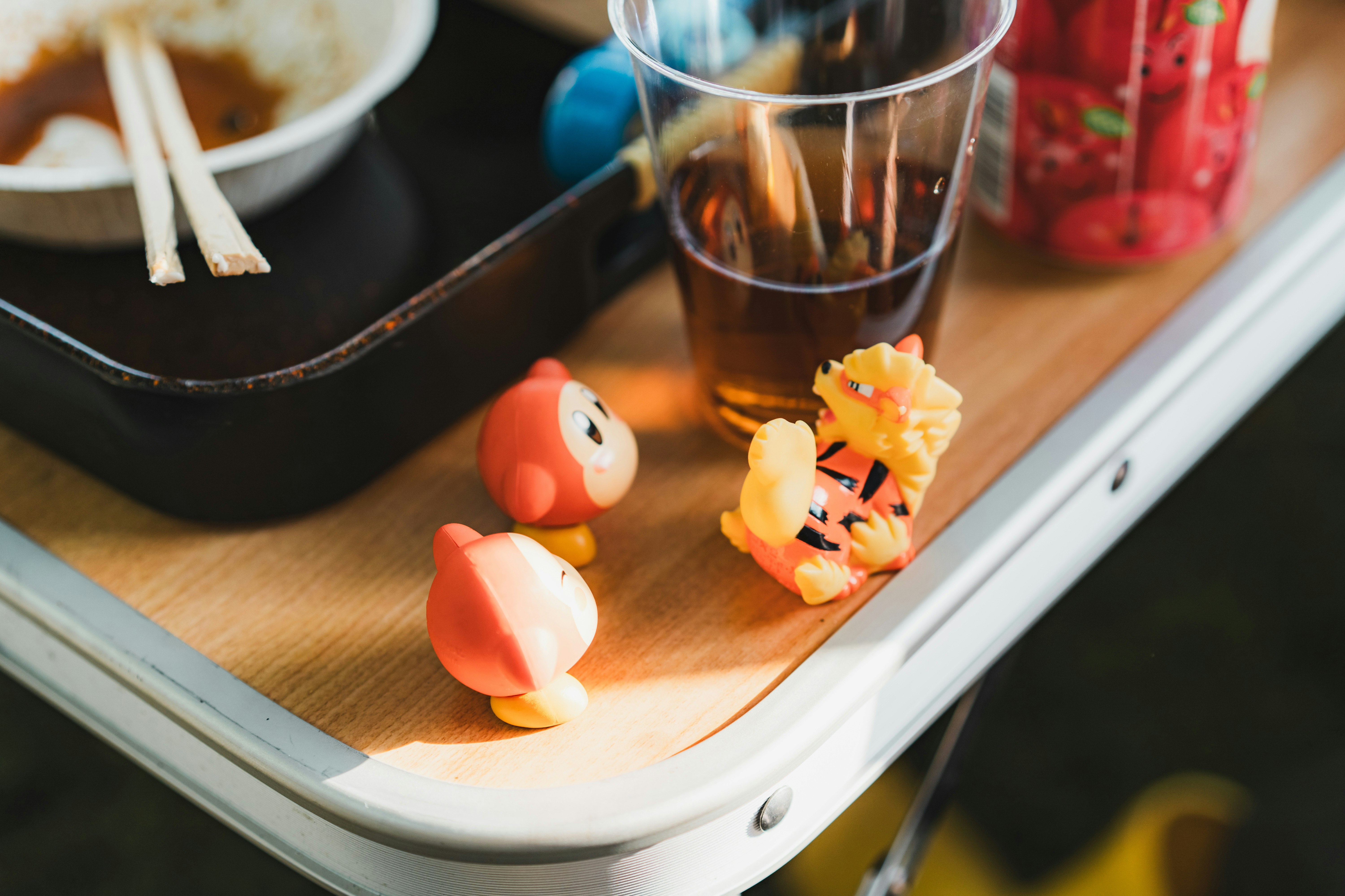 木製トレイに並ぶ小さなおもちゃフィギュアと食卓の雰囲気