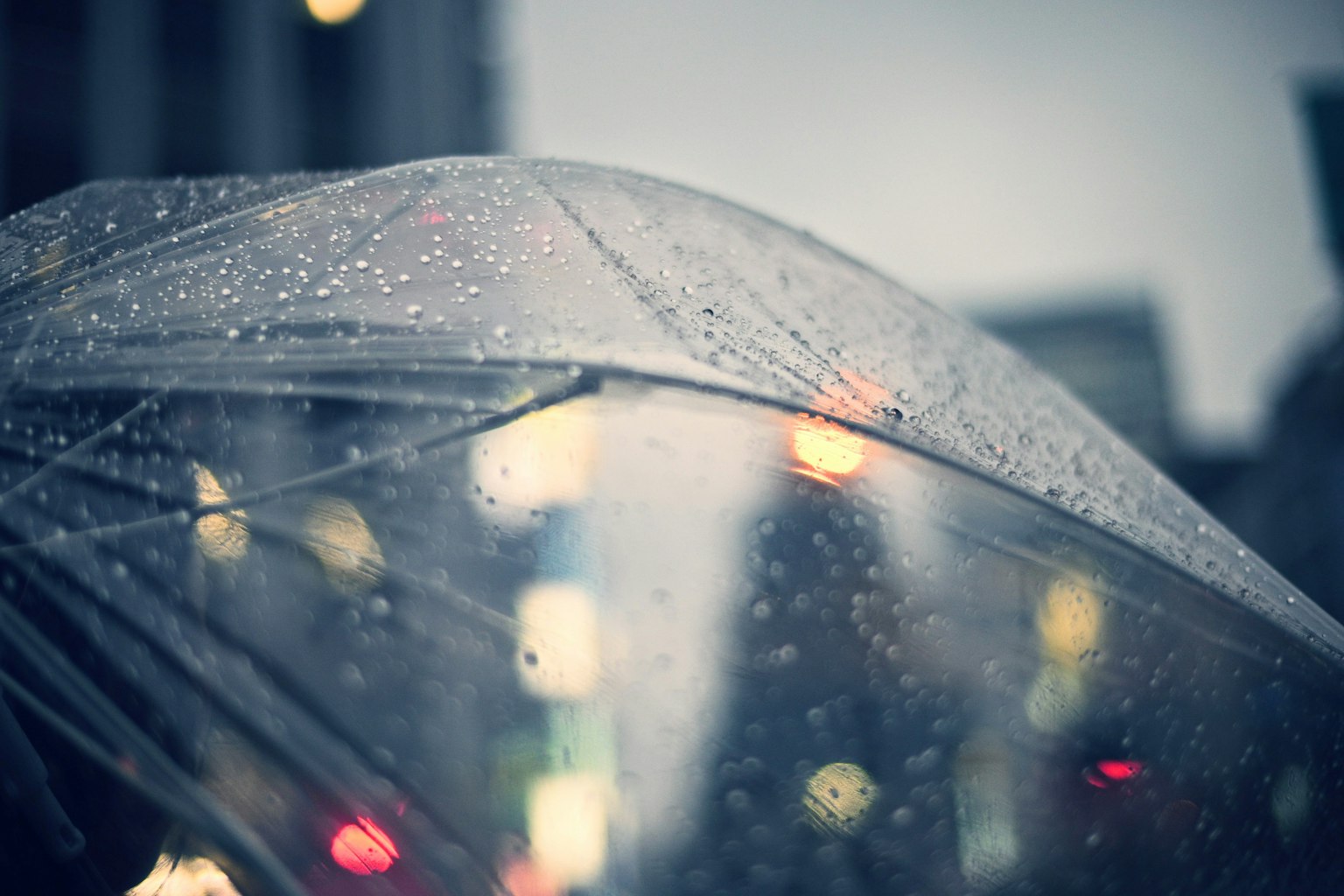 透明雨伞在雨中与模糊的城市灯光