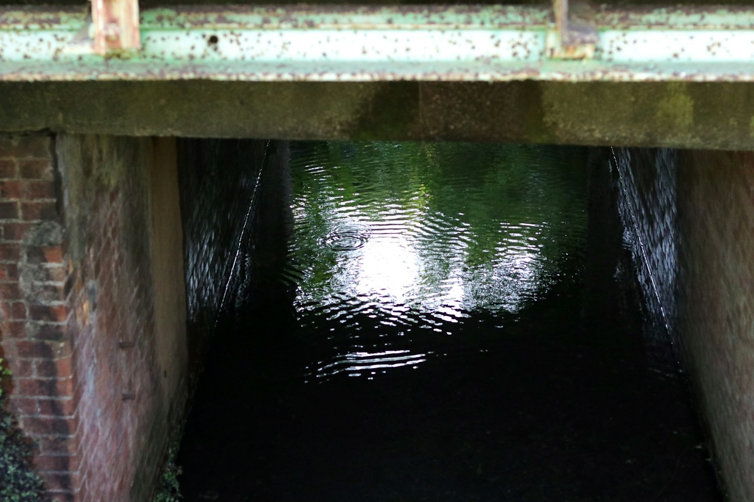 Eingang zu einem dunklen Tunnel mit Wasser, das Licht reflektiert
