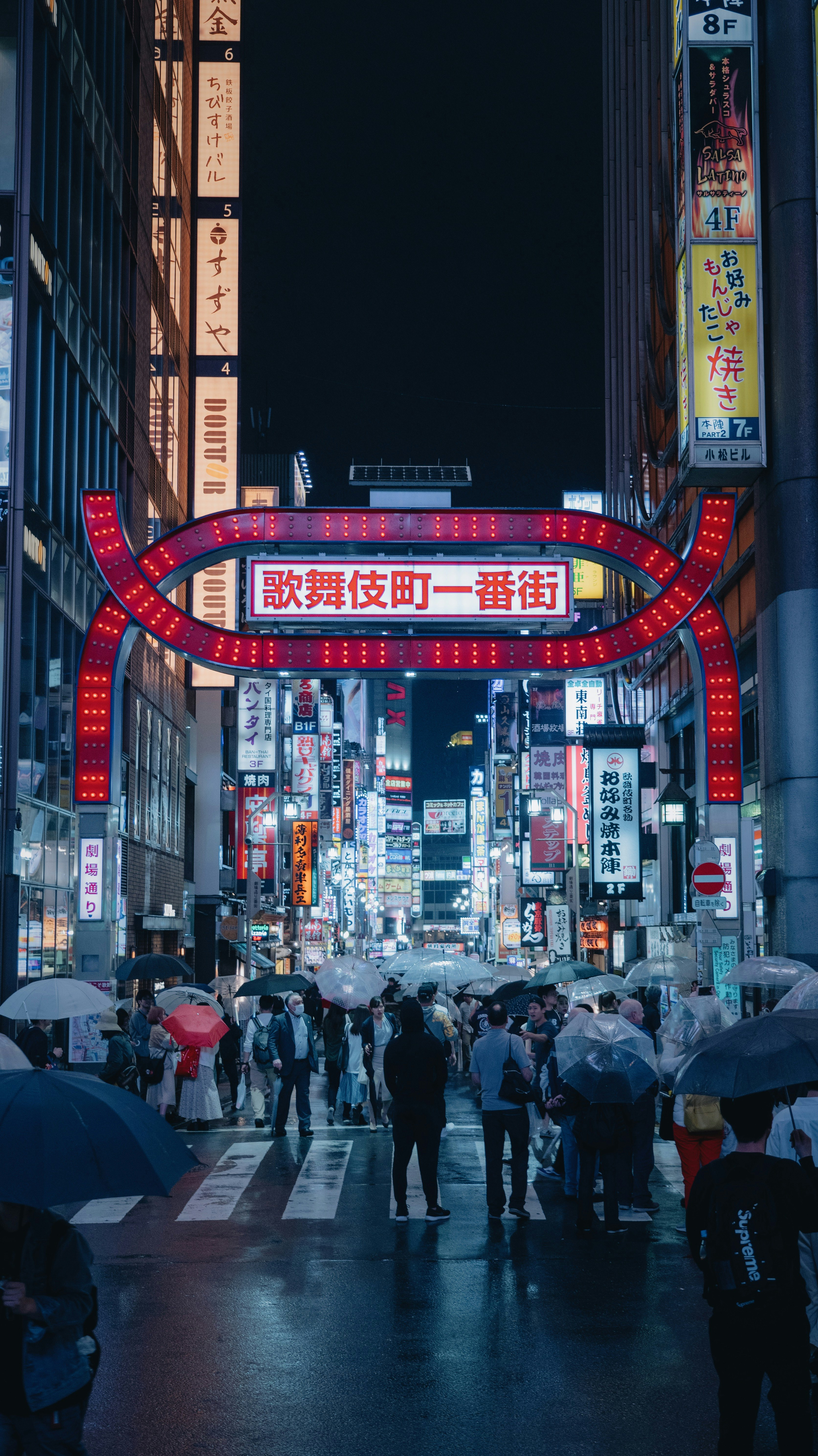 Crowd of people under a bright neon sign in a Tokyo shopping district