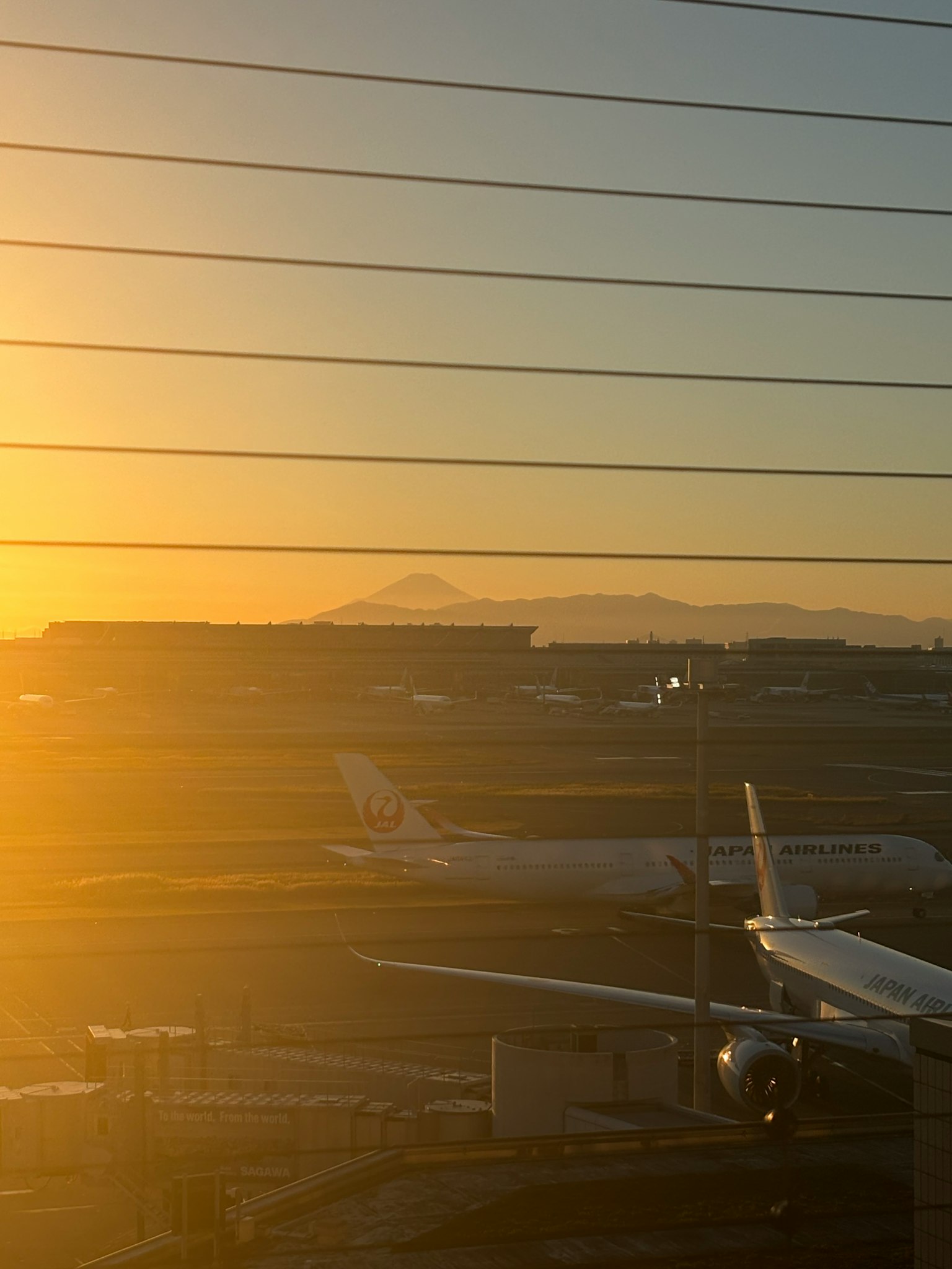 機場景觀，日落和遠處的山在飛機後面可見