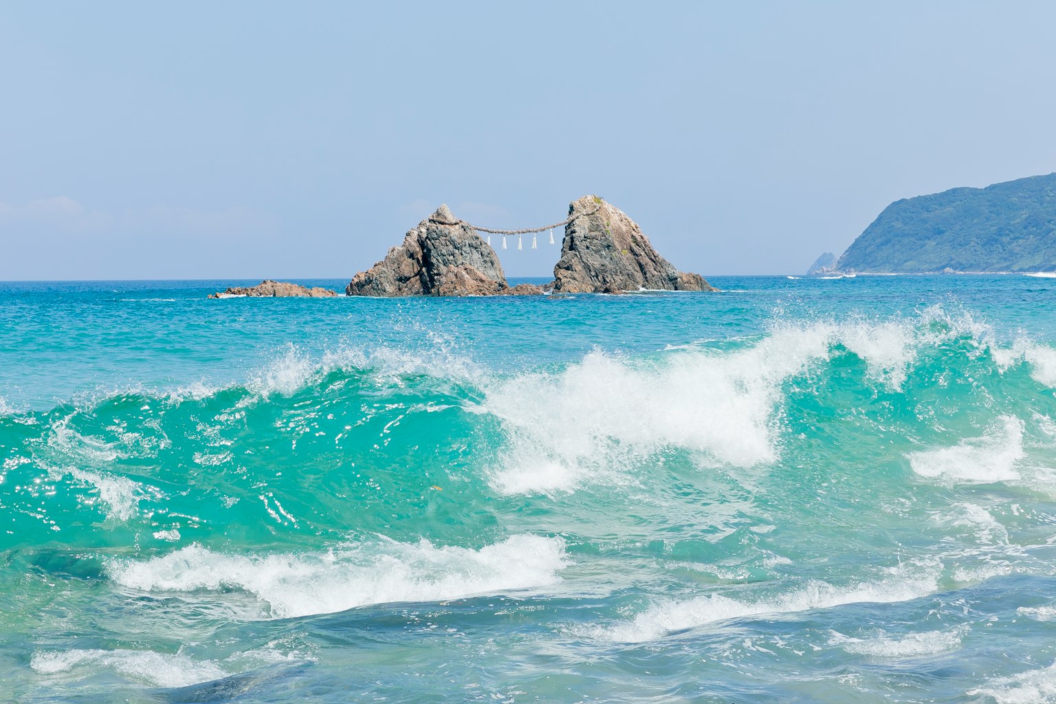 Vagues se brisant contre des formations rocheuses dans une mer turquoise