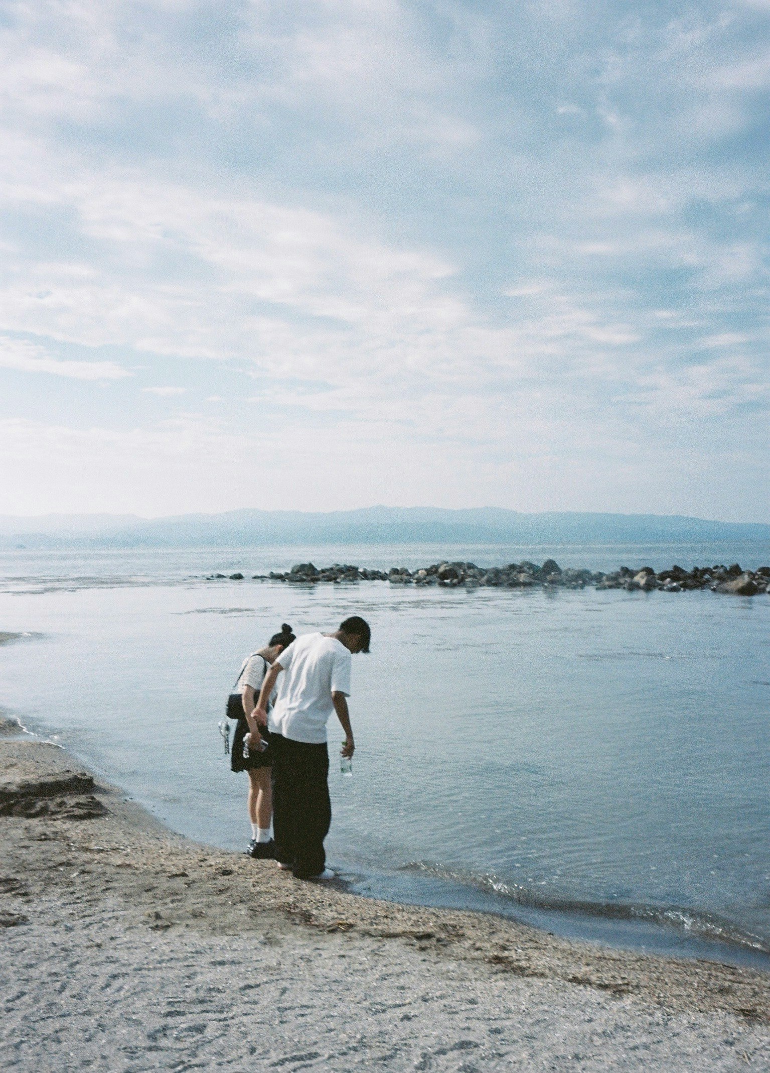 海辺を歩く人と穏やかな波の風景