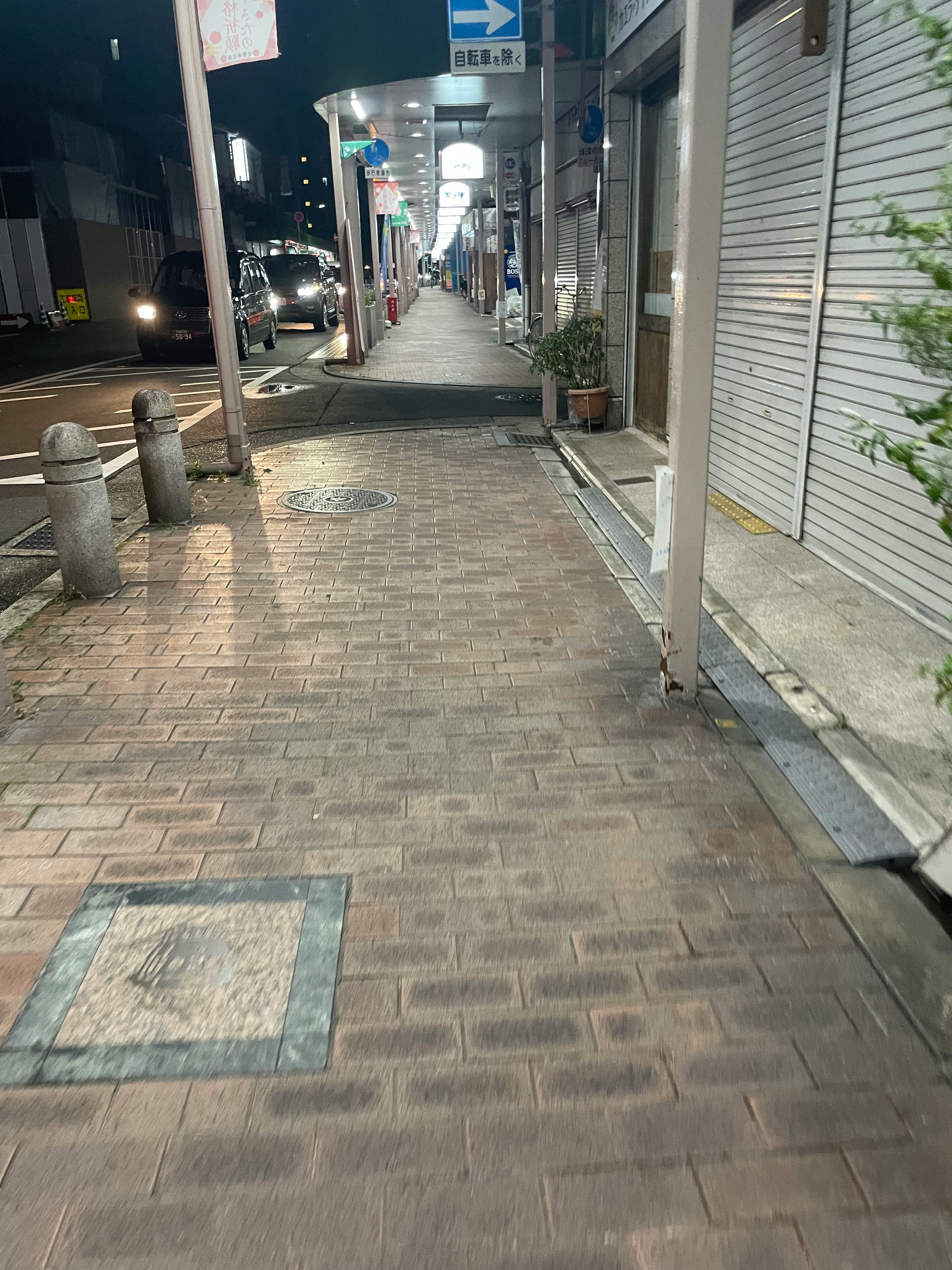 夜の商店街の並ぶシャッターと街灯のある路地