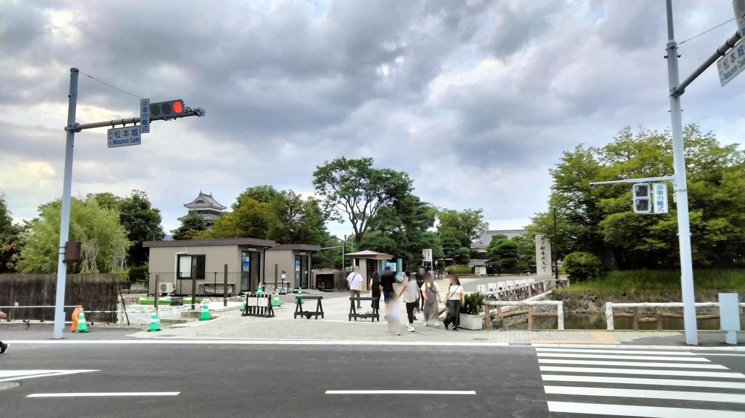 Crosswalk with people and lush greenery in the background