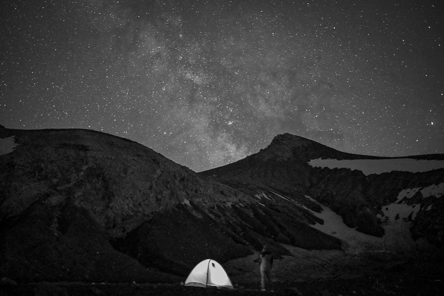 星空下的露营帐篷与轮廓分明的山脉