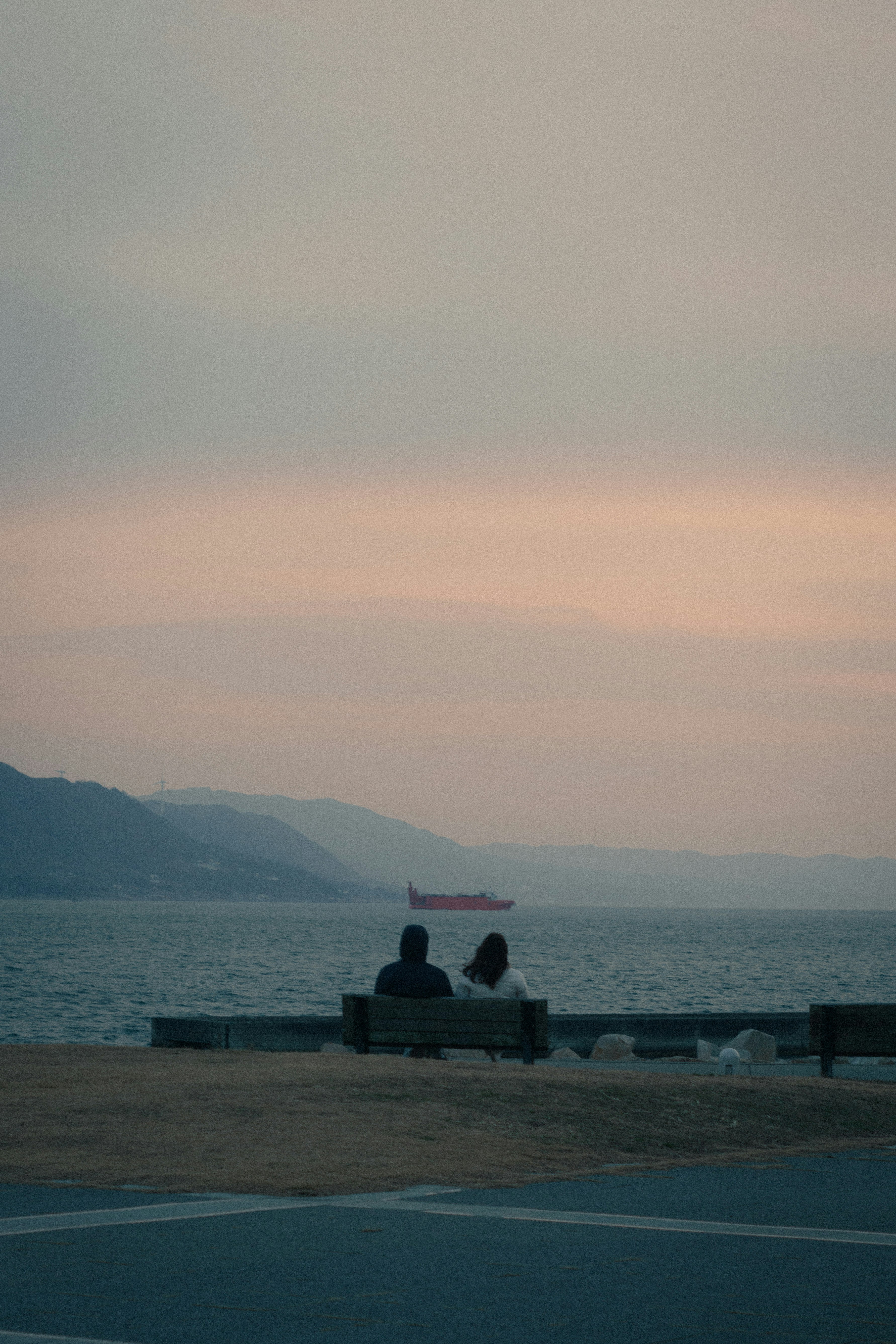 海を見つめるカップルのシルエットと穏やかな夕焼け