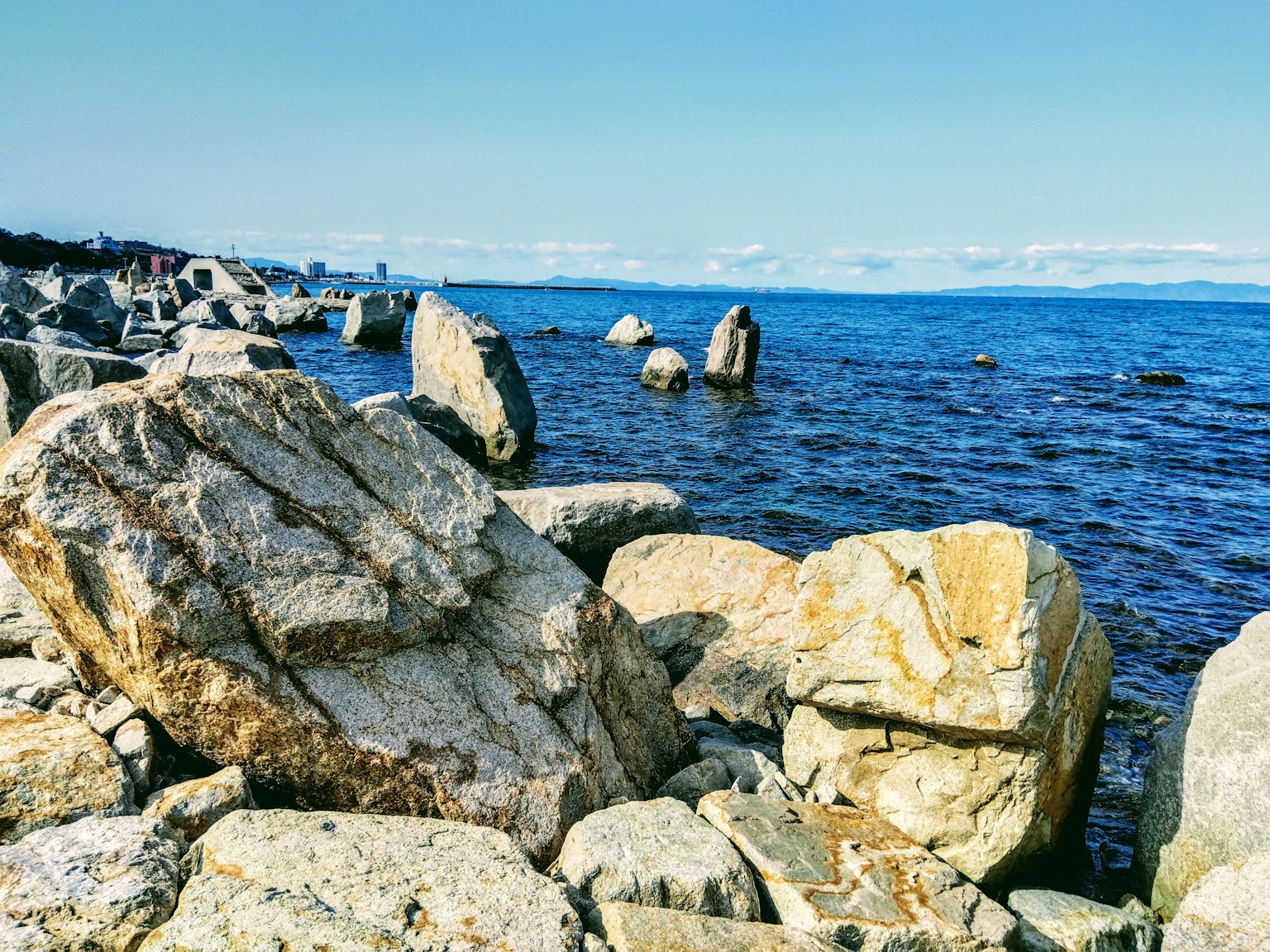 Scenic view of rocks by the sea under a clear blue sky