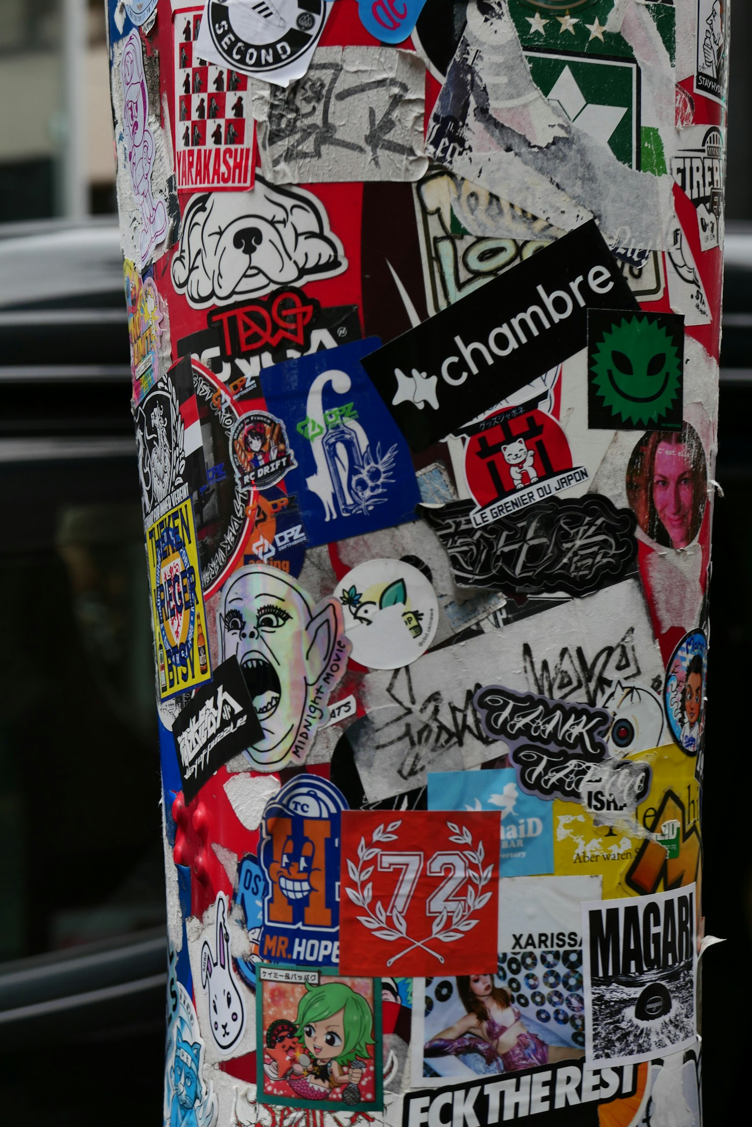 A section of a utility pole covered in colorful stickers and graffiti