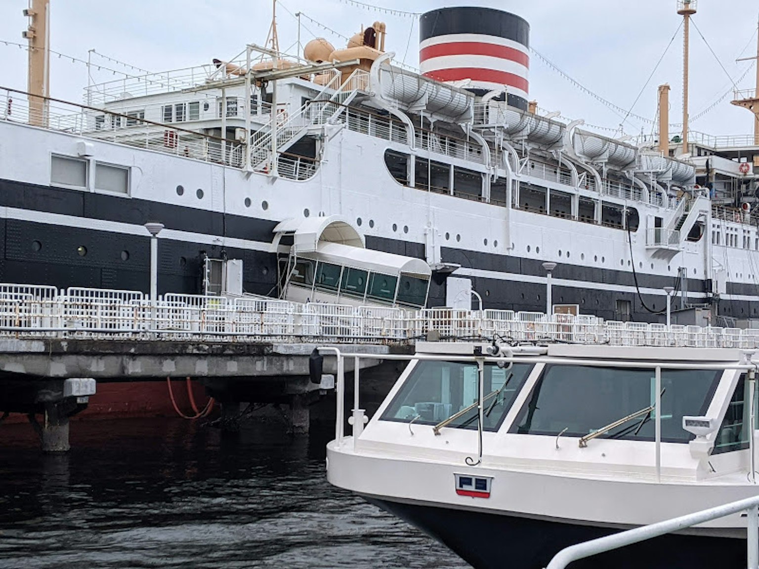 Un barco de pasajeros blanco y negro atracado con un pequeño bote en primer plano