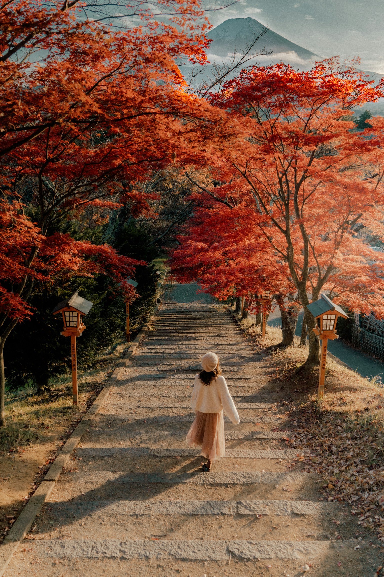 Una donna che cammina lungo un sentiero circondato da foglie autunnali con il monte Fuji sullo sfondo