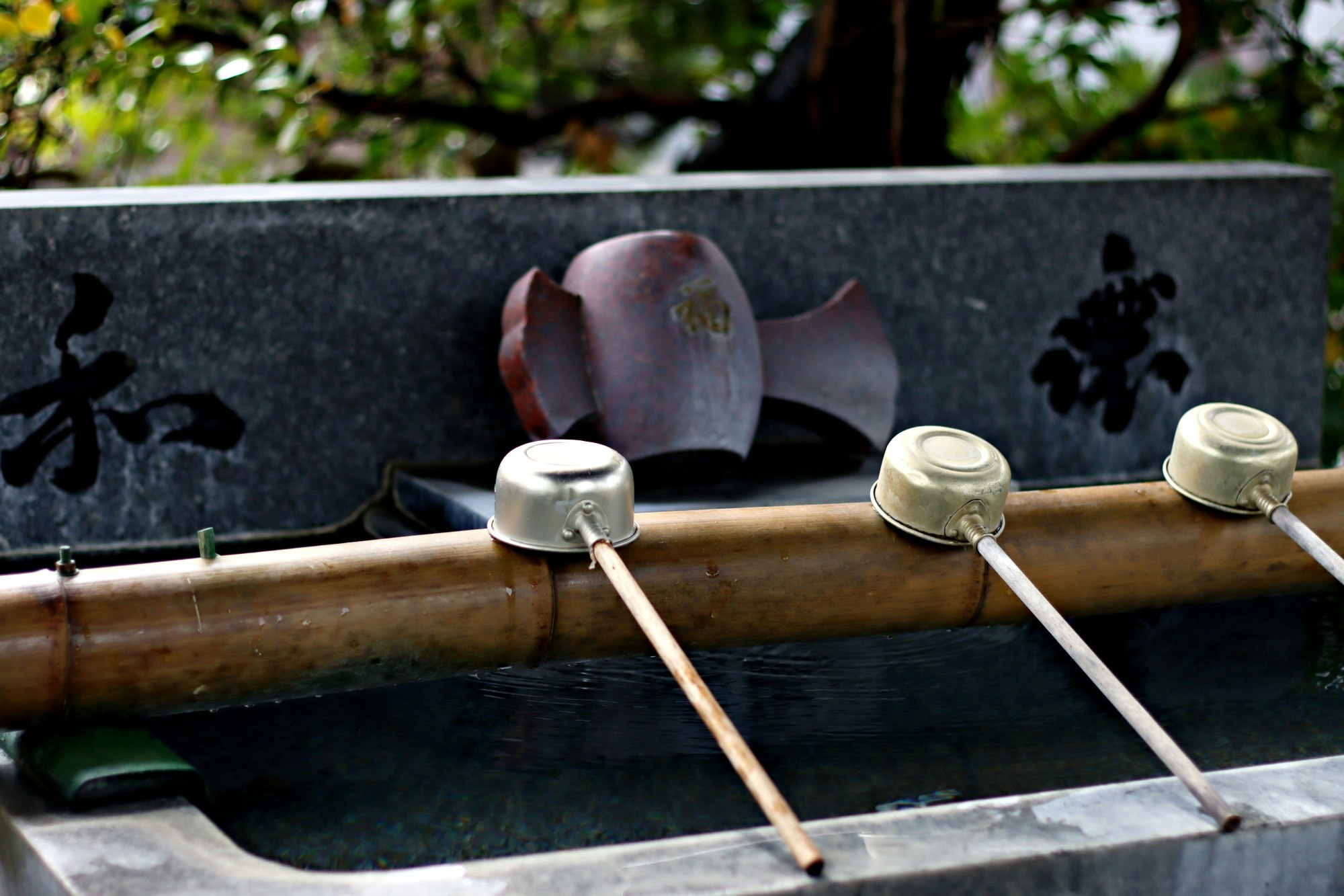 bamboo water basin with ladles and mossy stone water trough