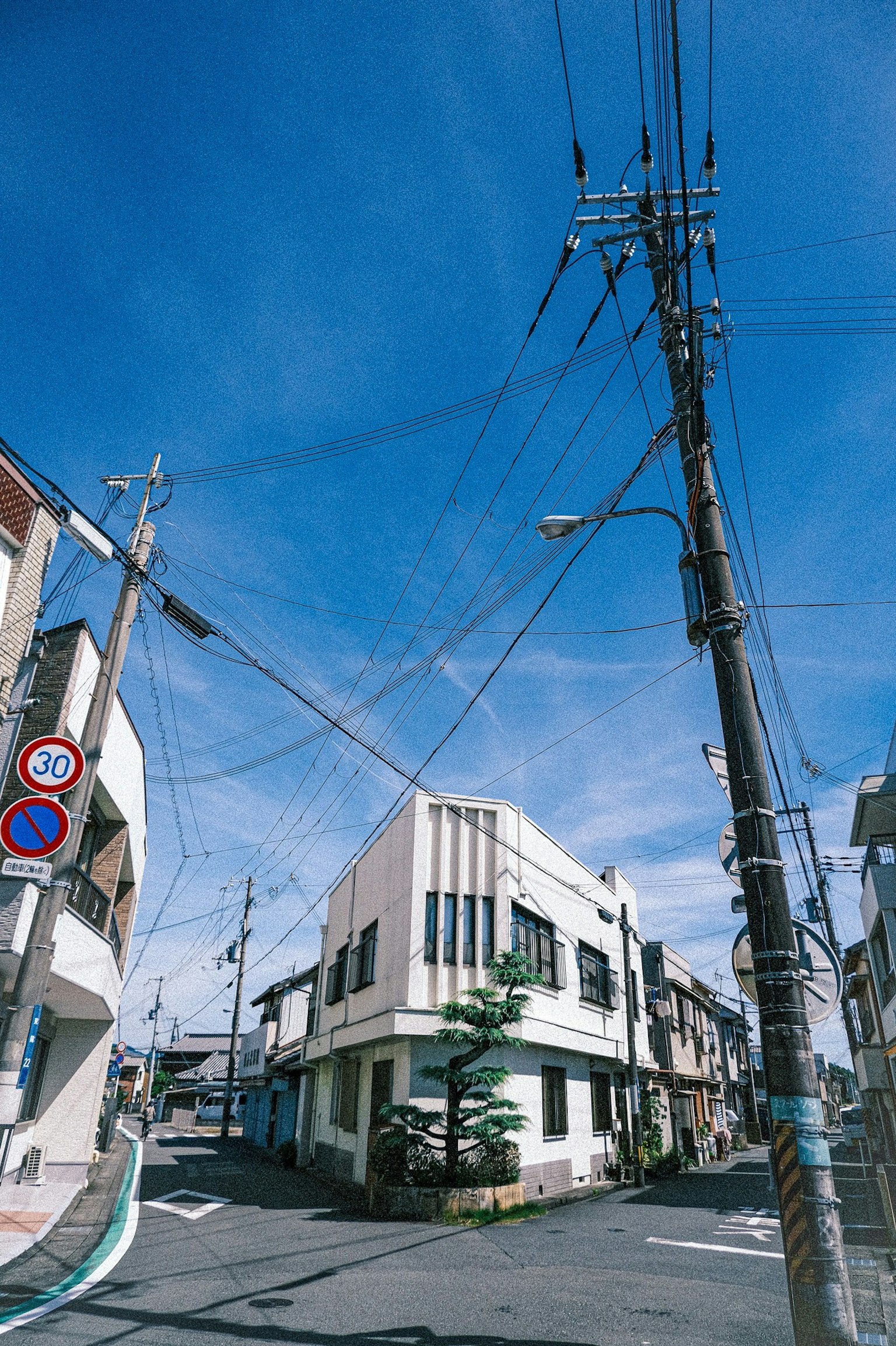 ทิวทัศน์ถนนที่แยกซึ่งมีอาคารเก่าและเสาไฟฟ้าใต้ท้องฟ้าสีฟ้า