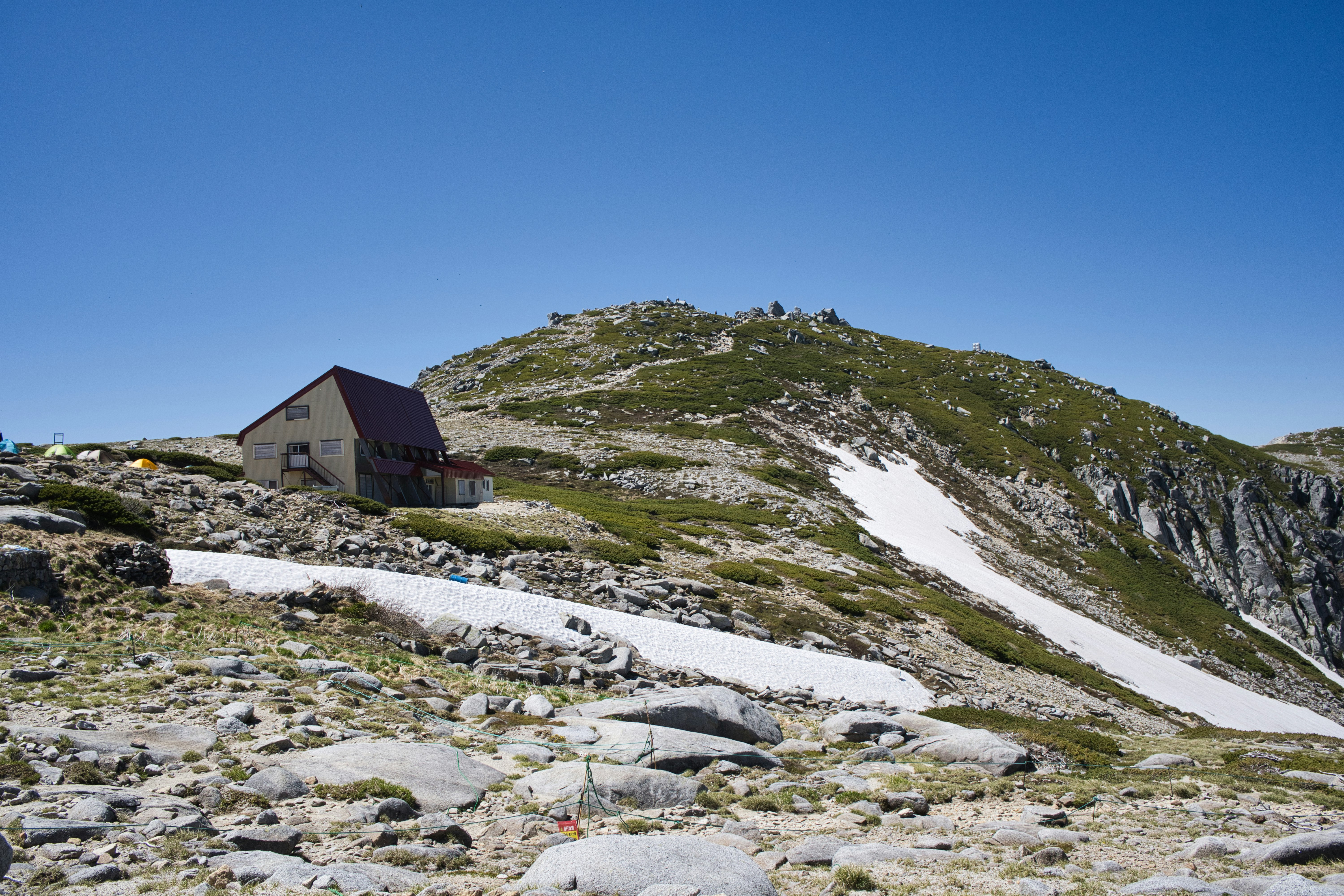 rocky mountain trail with a small cabin in alpine landscape